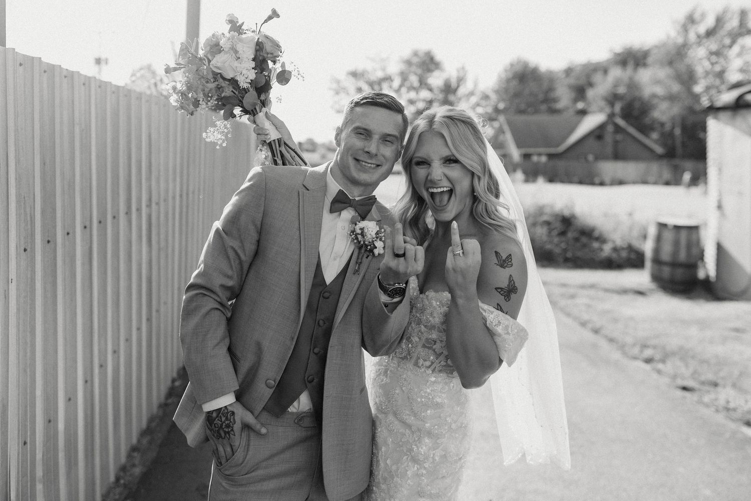 Joyful wedding celebration captured in black and white against rustic fence.