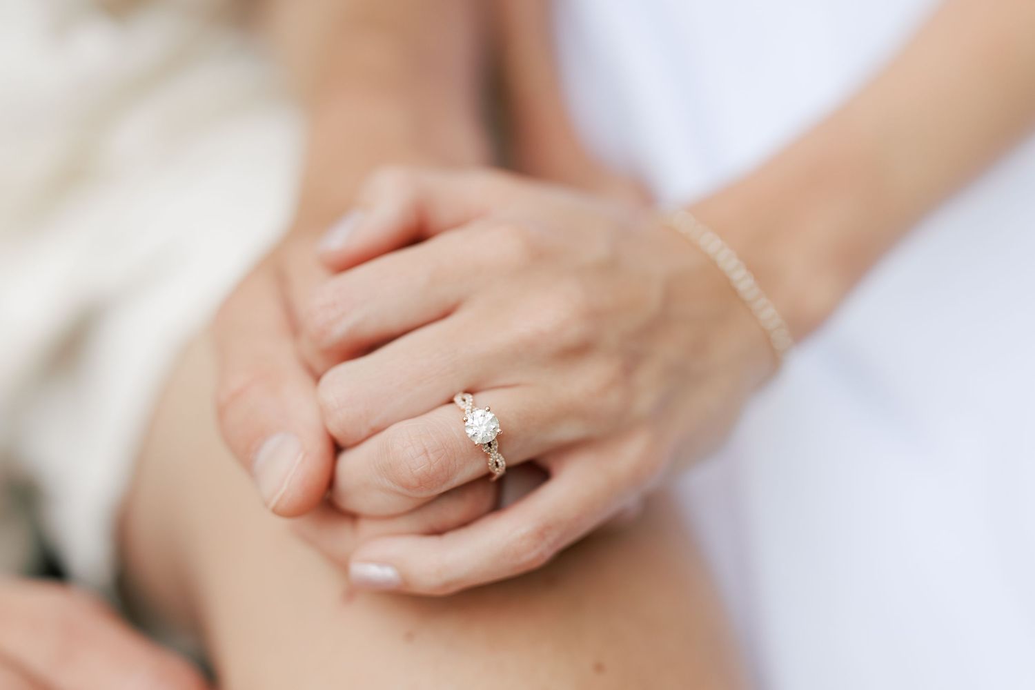 Close-up of an elegant diamond engagement ring on a woman's finger, with soft natural lighting.
