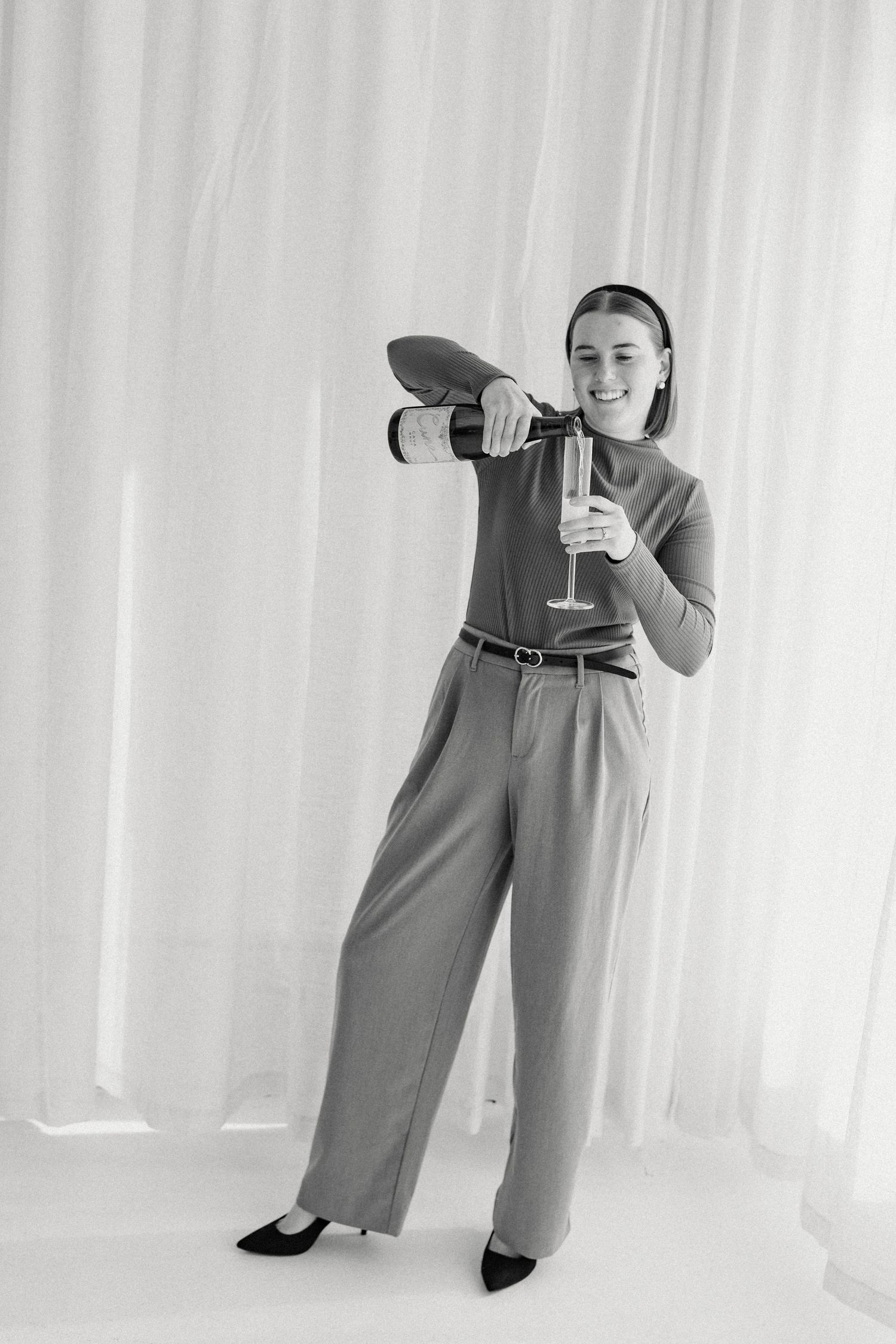 Black and white portraits showing playful poses with wine glass against white backdrop.