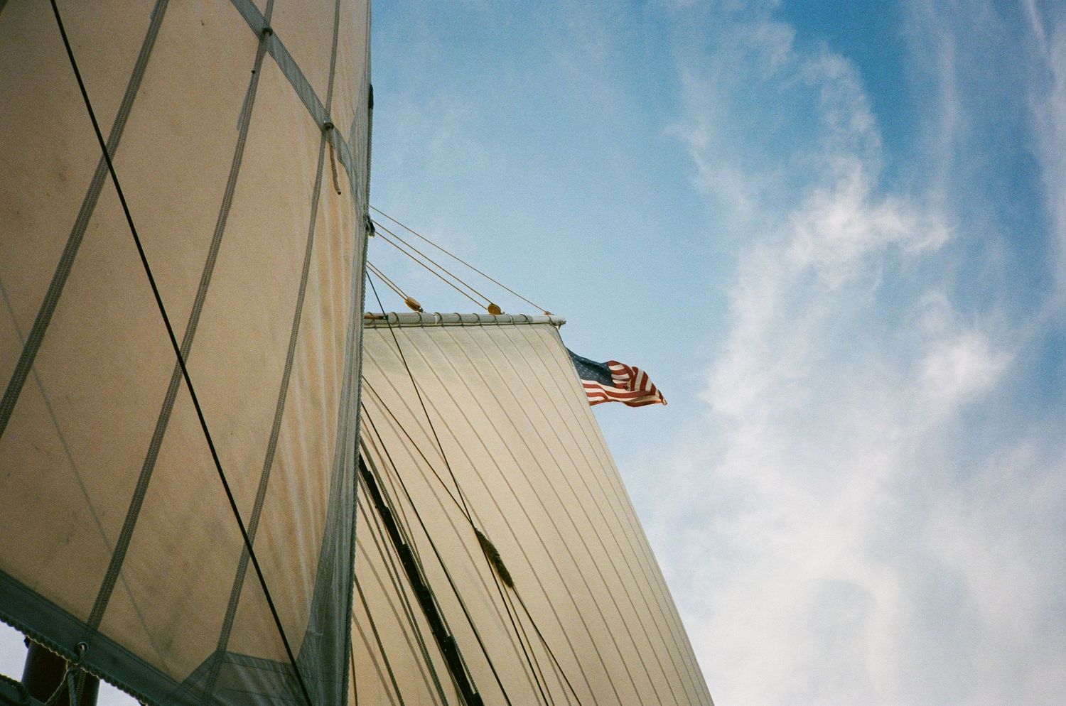 American flag flying above a large white wedding tent against a blue sky with clouds.