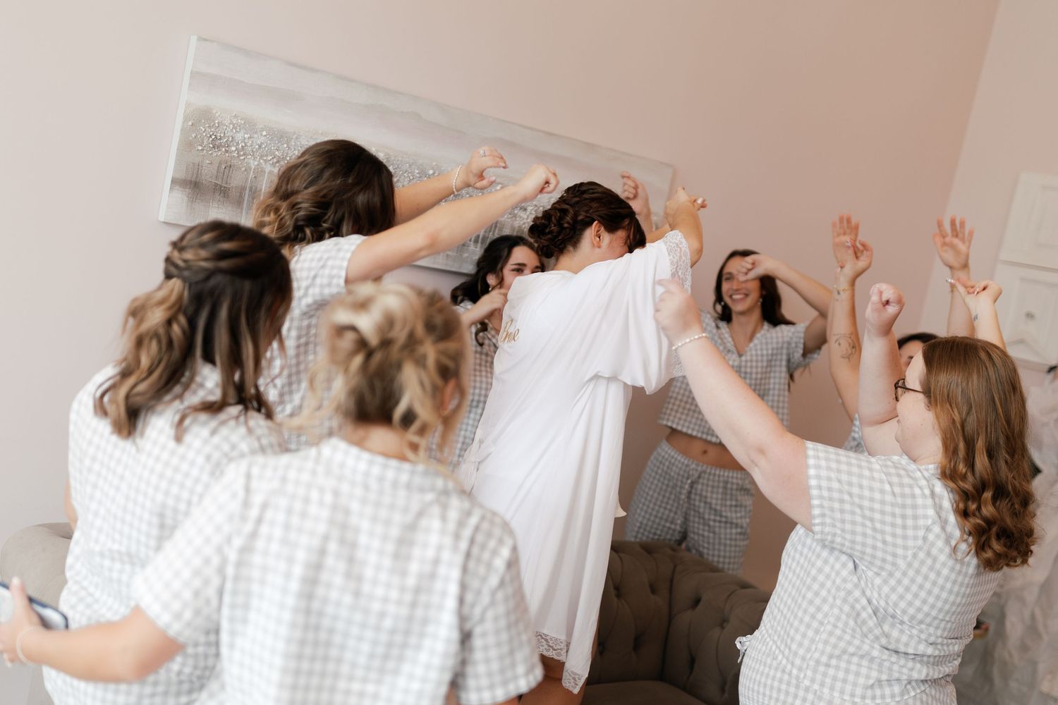 A group wearing matching white outfits dances with arms raised in celebration.