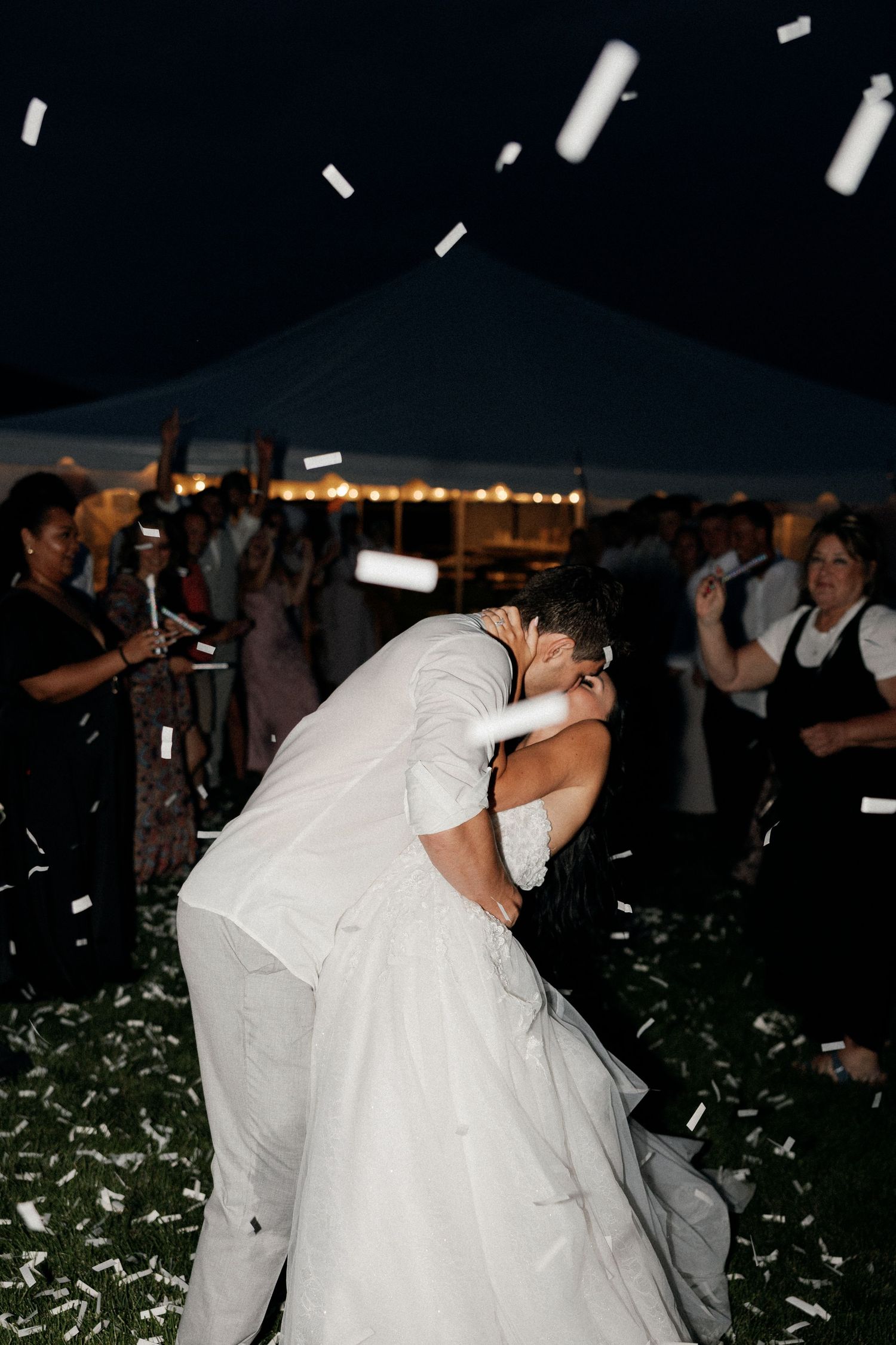 Wedding celebration at night with confetti falling under tent lighting.