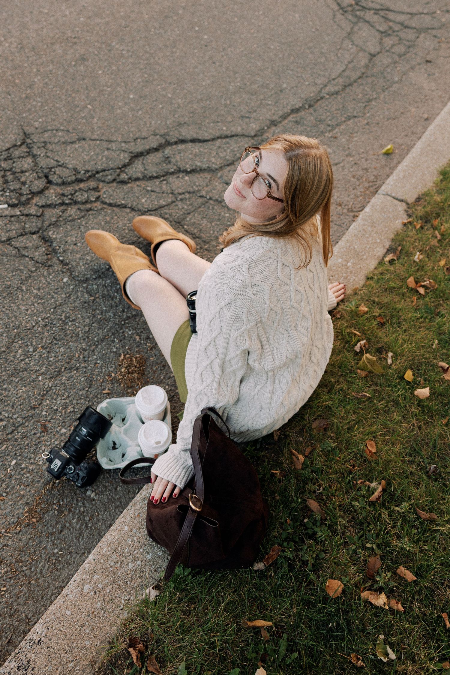 Casual outdoor photoshoot featuring cream sweater and relaxed poses on concrete curb.