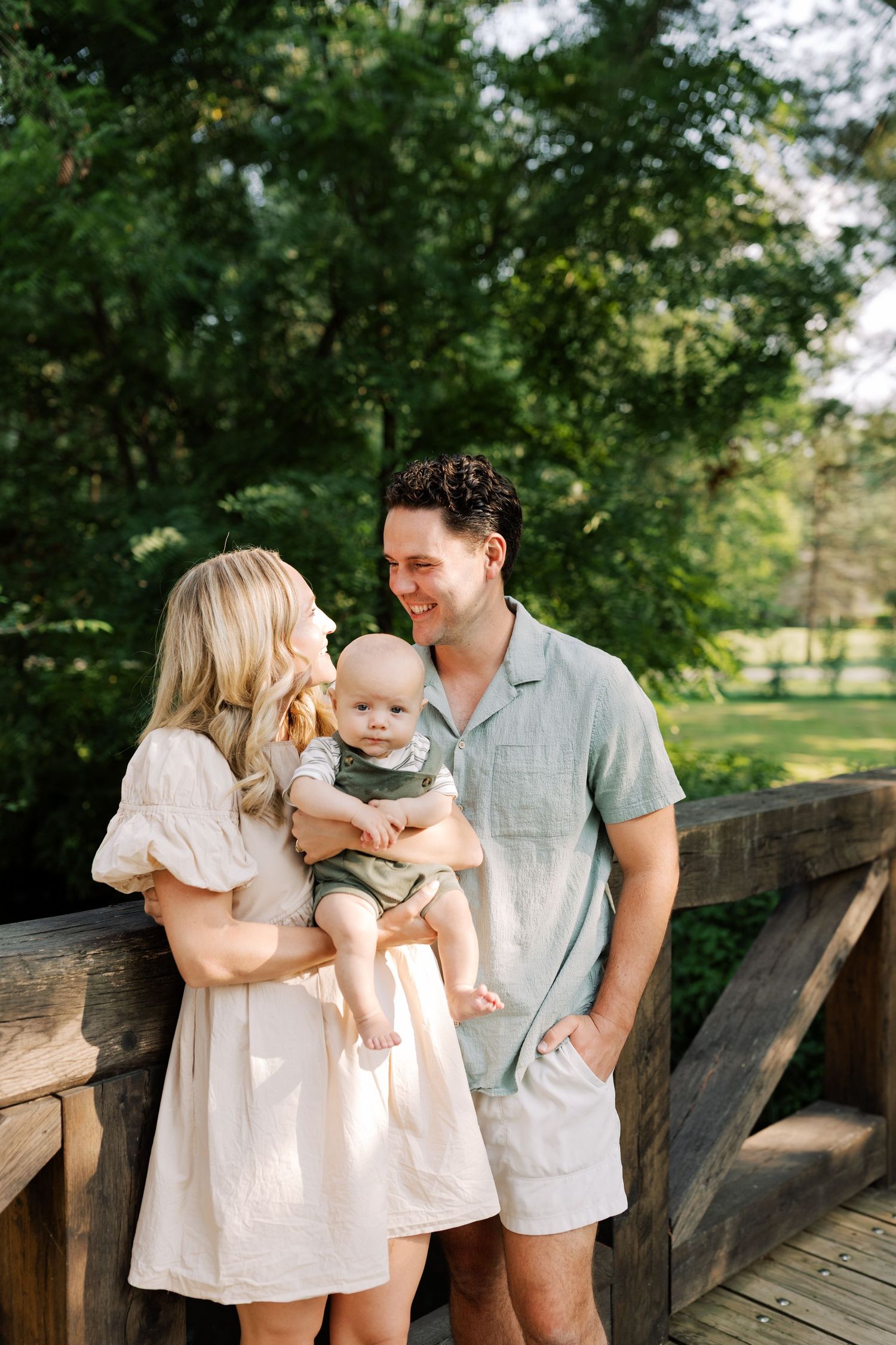 Intimate family portraits on a rustic wooden bridge surrounded by lush summer greenery.