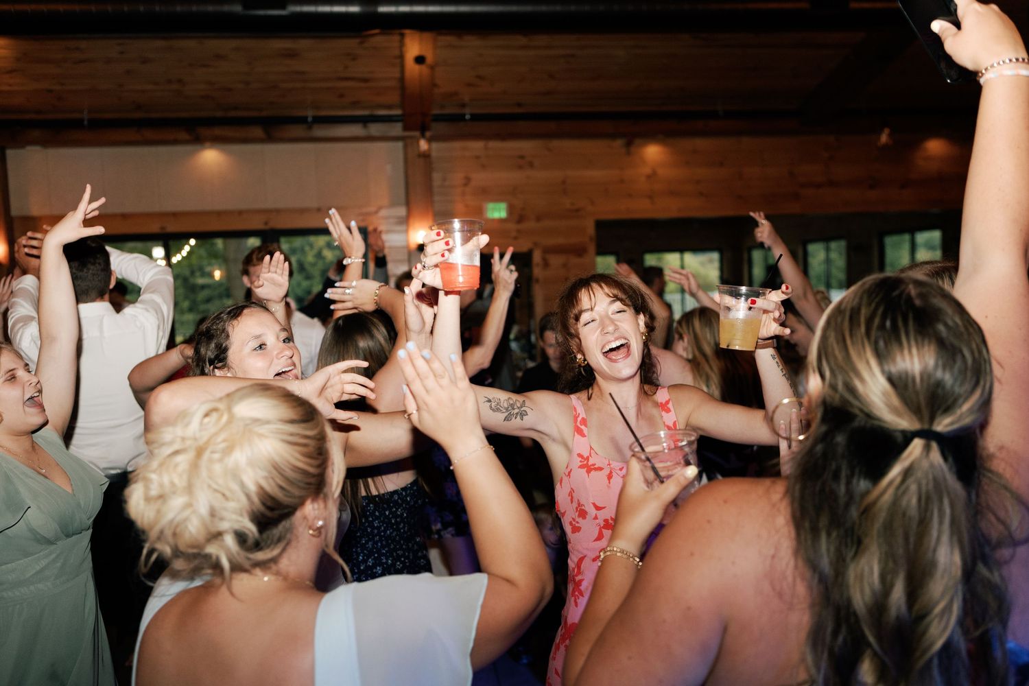 Wedding reception dance party with guests celebrating on dance floor under warm lighting.