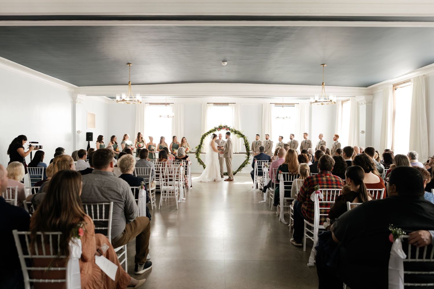 Wedding reception venue with white decor and rows of tables set for a celebration.
