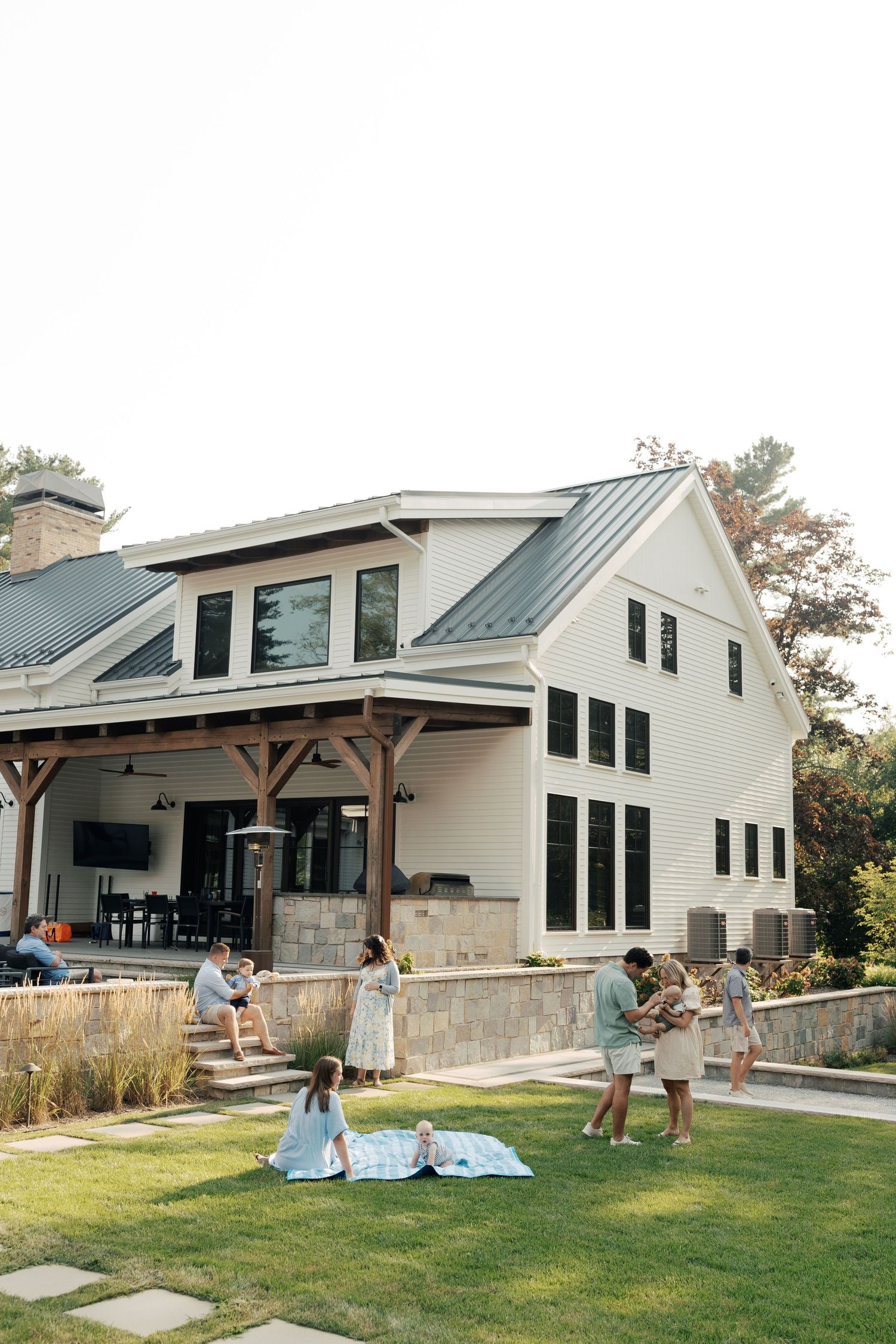 Modern farmhouse exterior with white siding and large windows surrounded by landscaped yard.