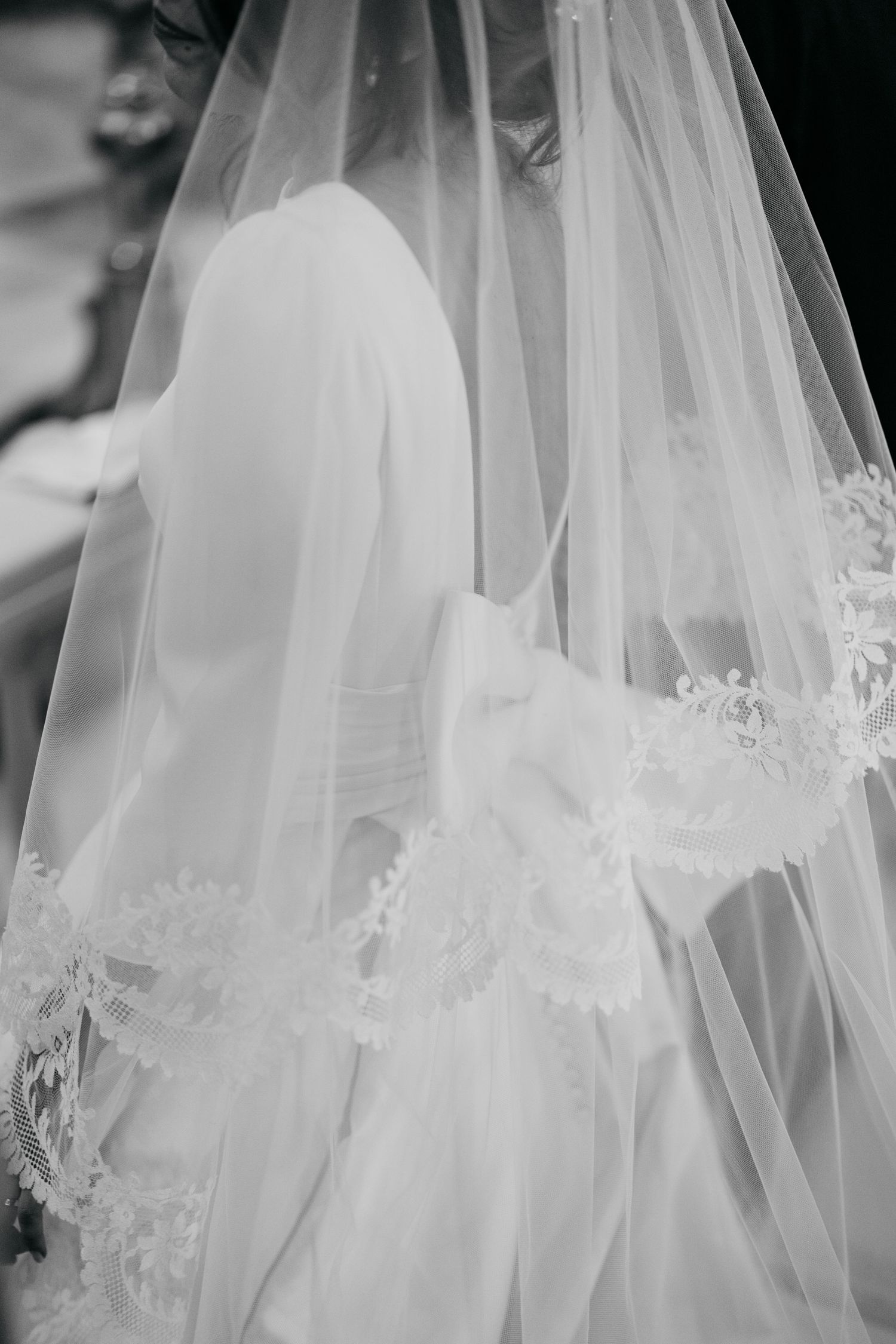 Black and white close-up of a bride wearing a lace-trimmed wedding veil.