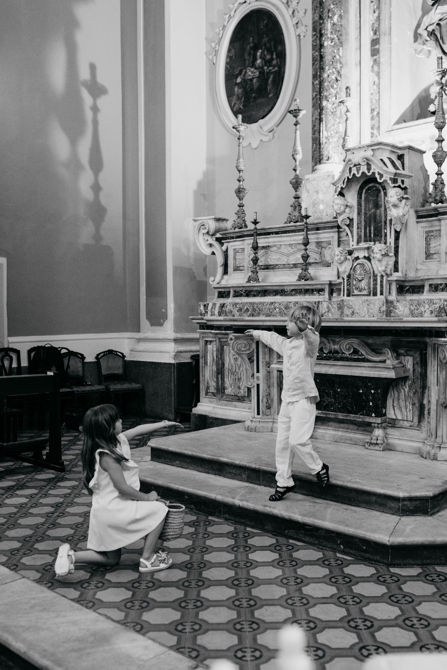 Two children playing near a ornate church altar in black and white photo.