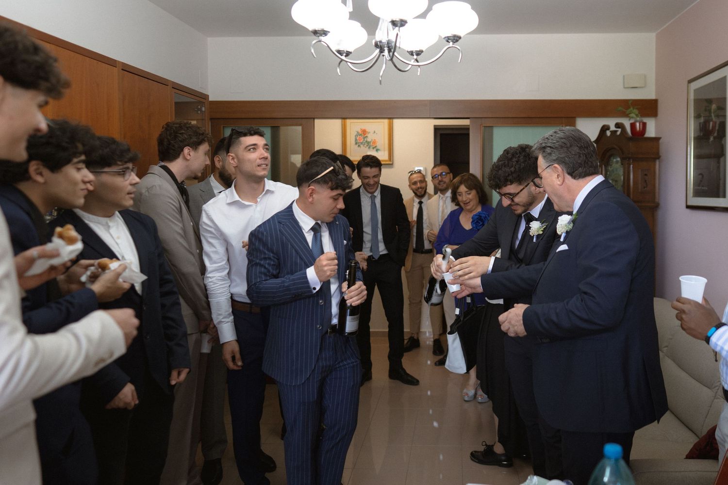 Business professionals in suits mingle and network during a corporate event in a brightly lit indoor space.