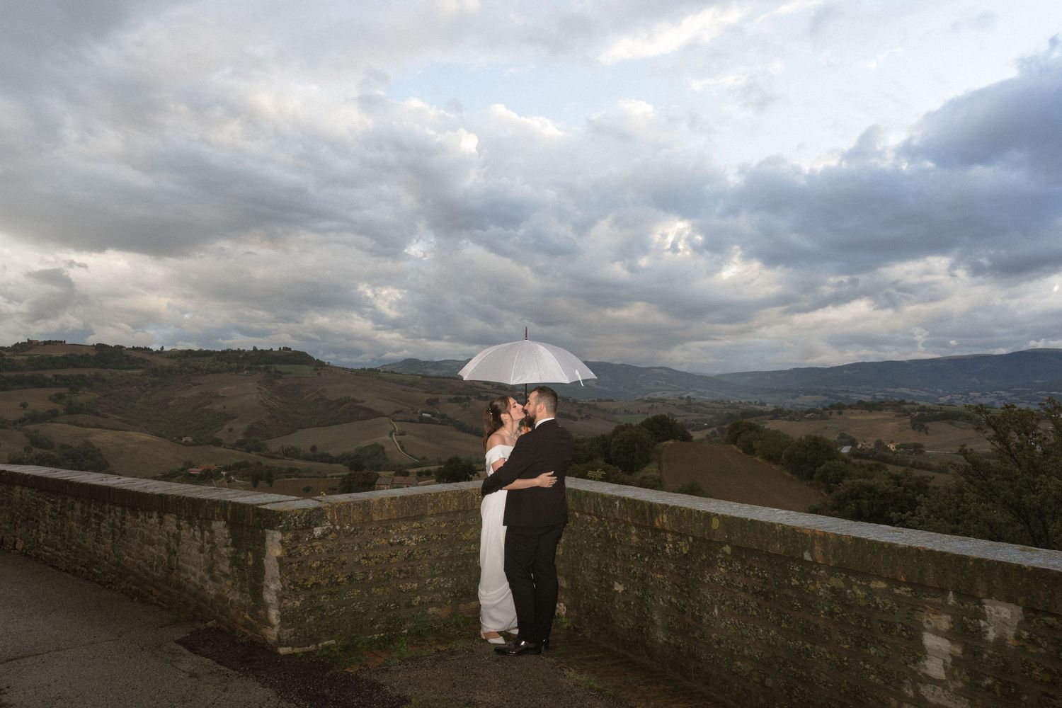 Panoramic view of rolling hills and cloudy skies from a stone wall overlook.