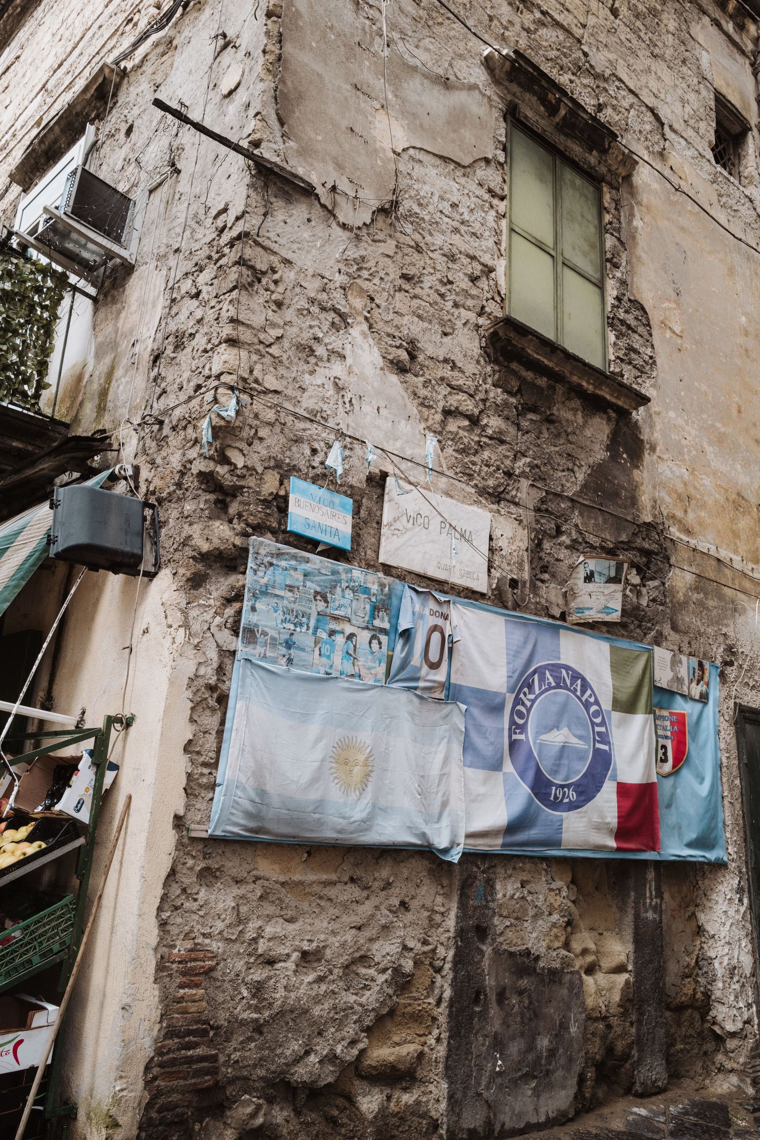 Laundry hanging on lines against a crumbling stone wall with peeling plaster.