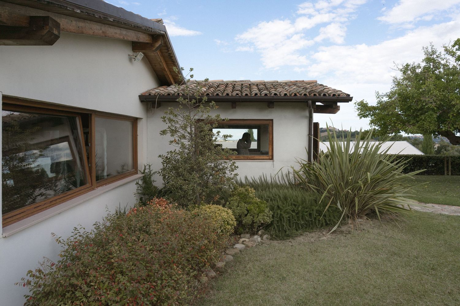 Modern white stucco house with rustic roof tiles and landscaped garden.