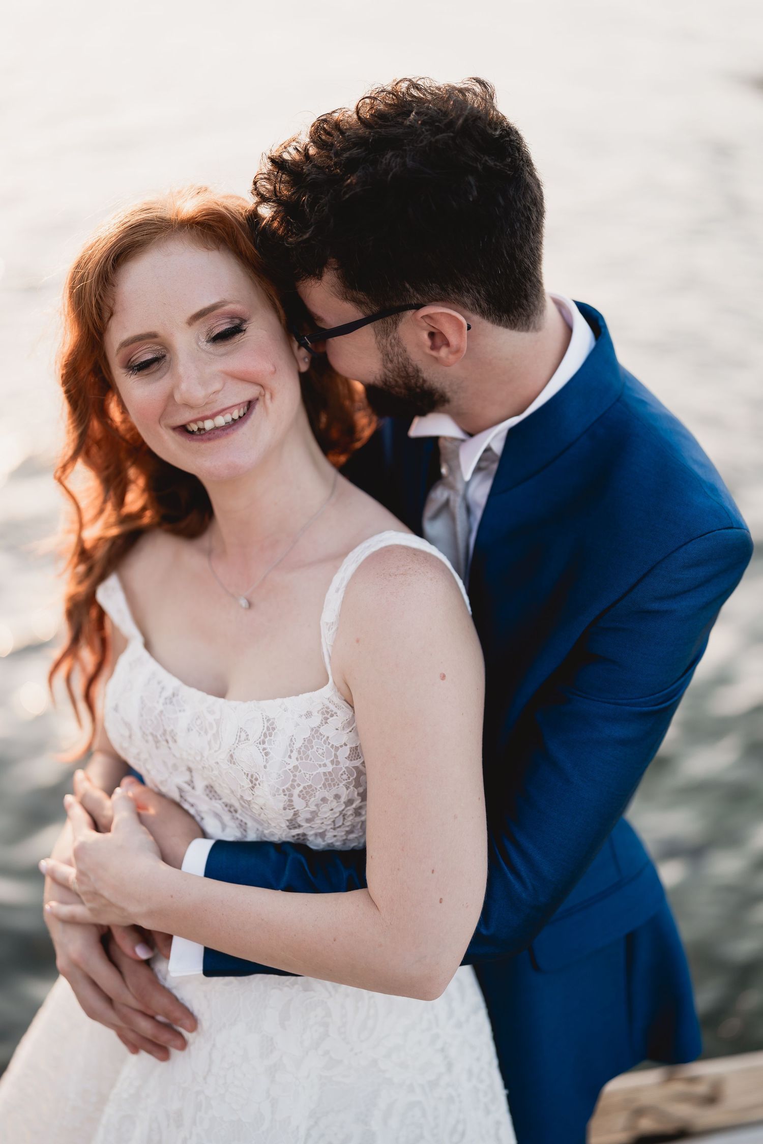 Intimate wedding moment captured between newlyweds against an ocean backdrop.