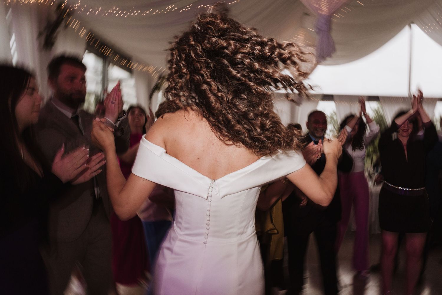 Person in white dress dancing with curly hair flying at reception.