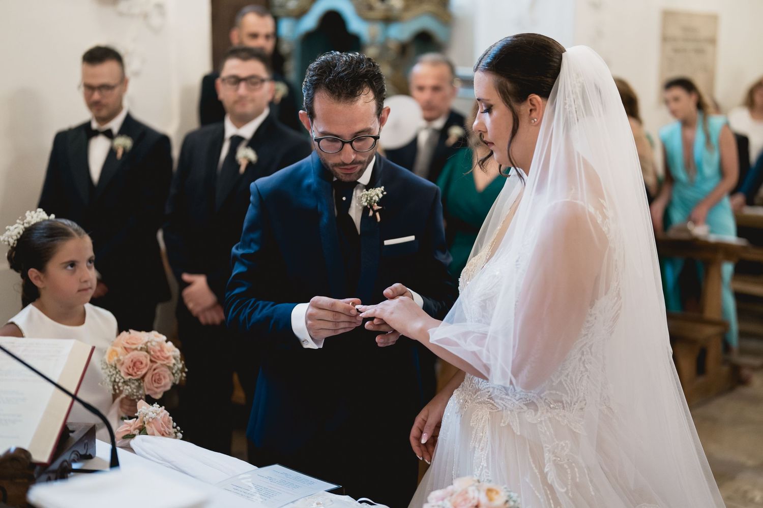 A wedding ceremony exchange takes place in a historic church with vaulted ceilings.