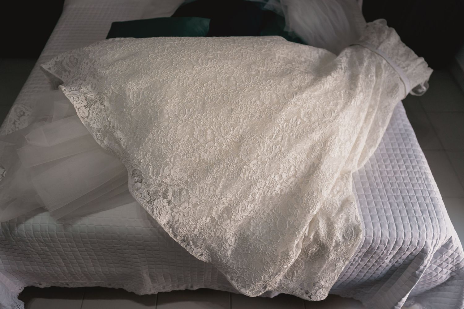 White lace wedding dress detail laying on textured fabric.