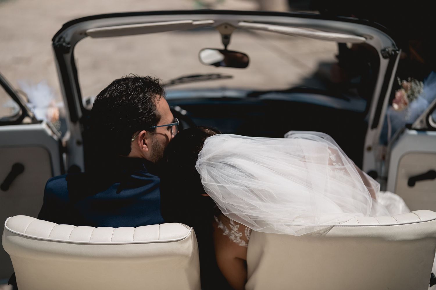 Close-up shot of a couple's intertwined hands in a vintage car.