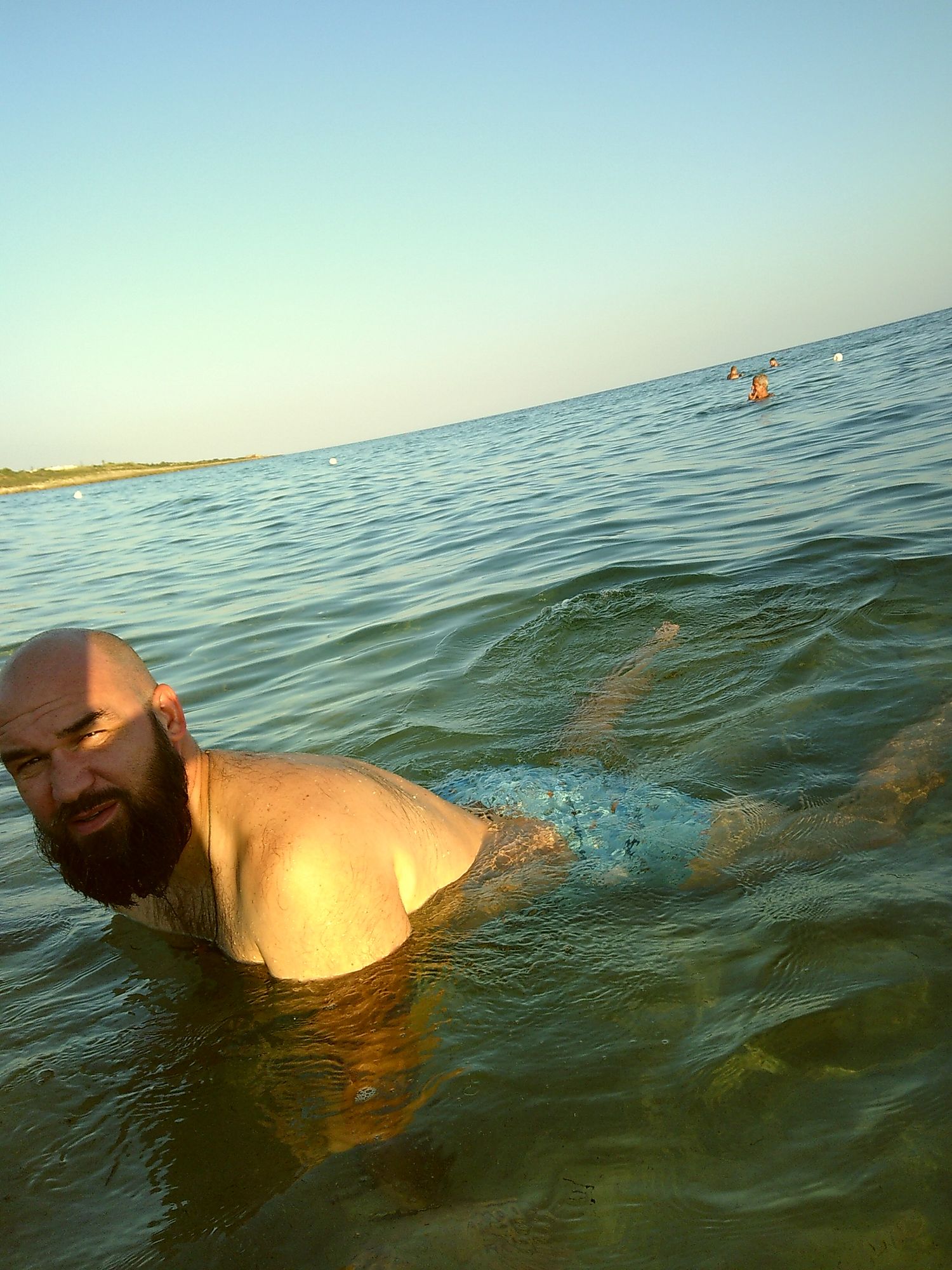 Someone swimming and enjoying the calm ocean waters during sunset.