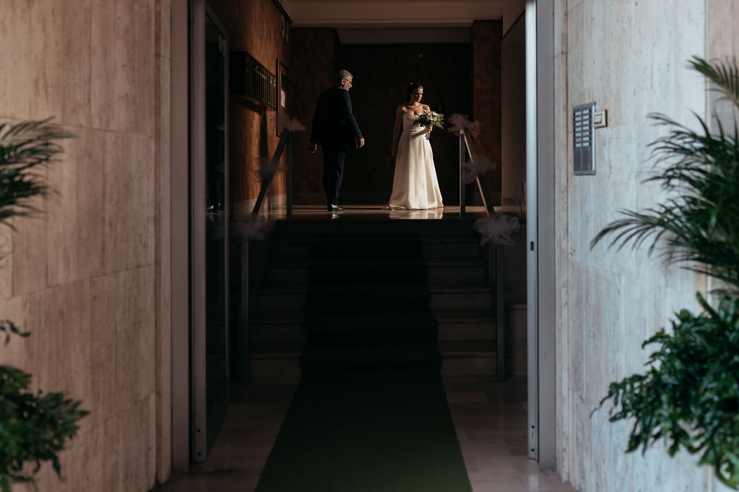 A dim hallway with a green carpet runner leading to stairs.