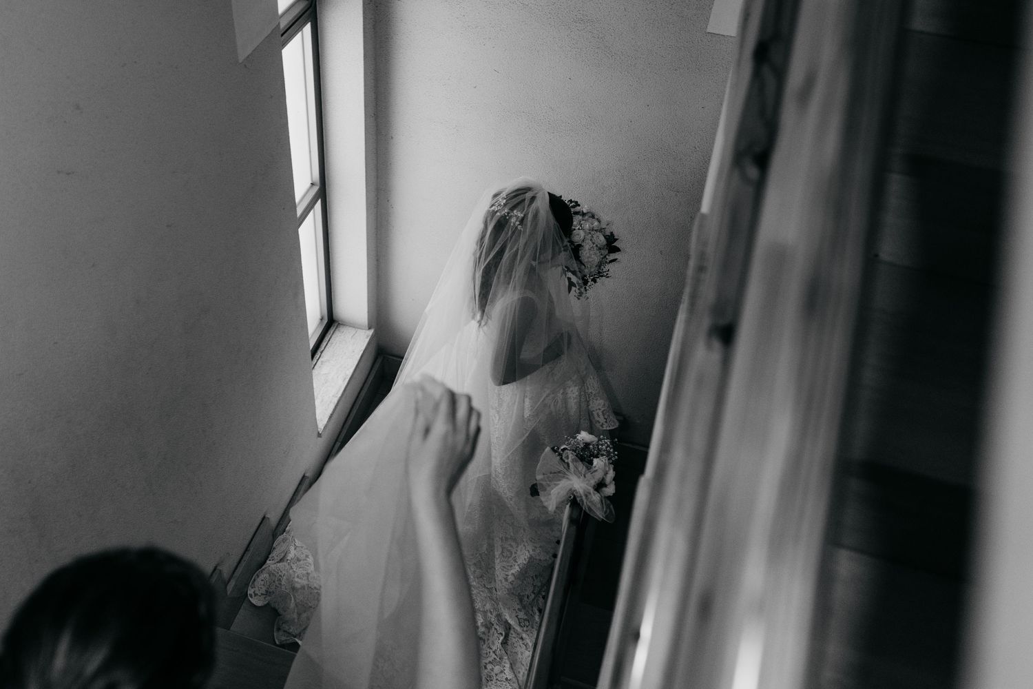 Artistic black and white photograph of wedding preparation through window reflection.