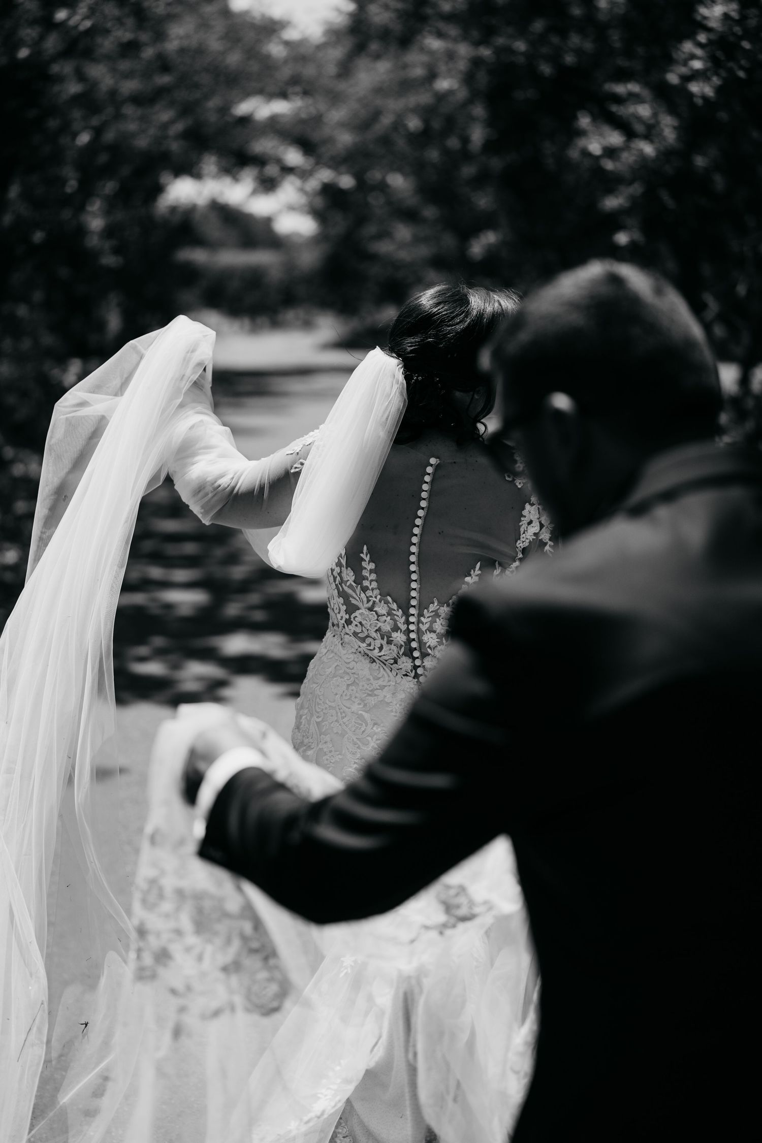 Black and white photo capturing the detail of a bride's beaded dress and flowing veil.