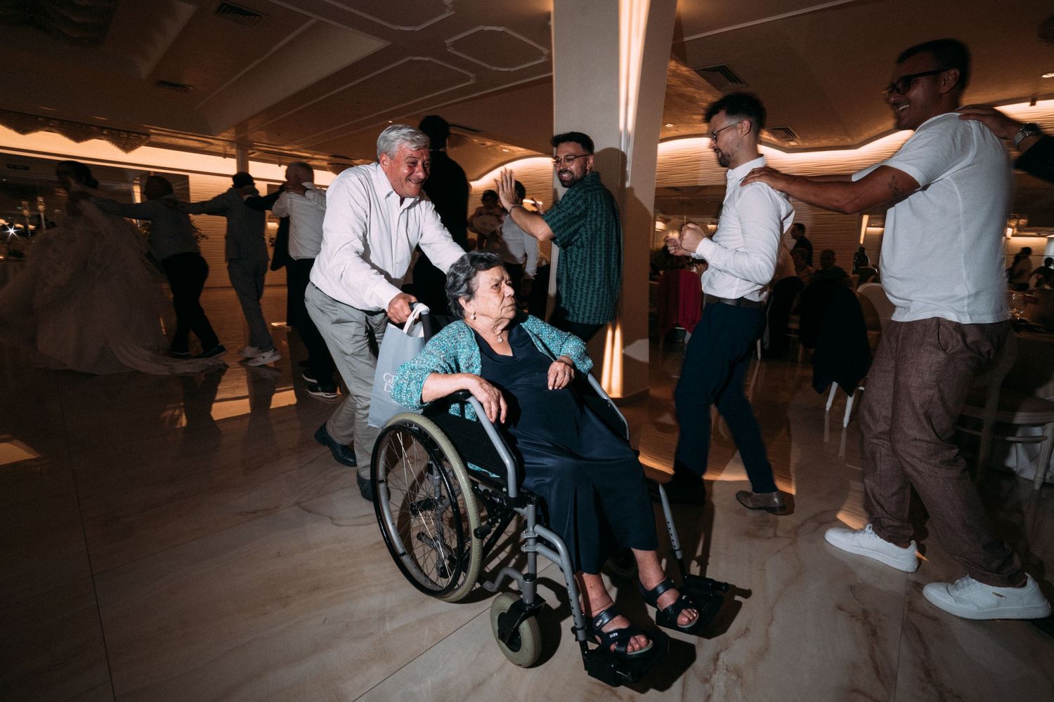 Wedding guests dancing and celebrating, including someone in a wheelchair joining the festivities.