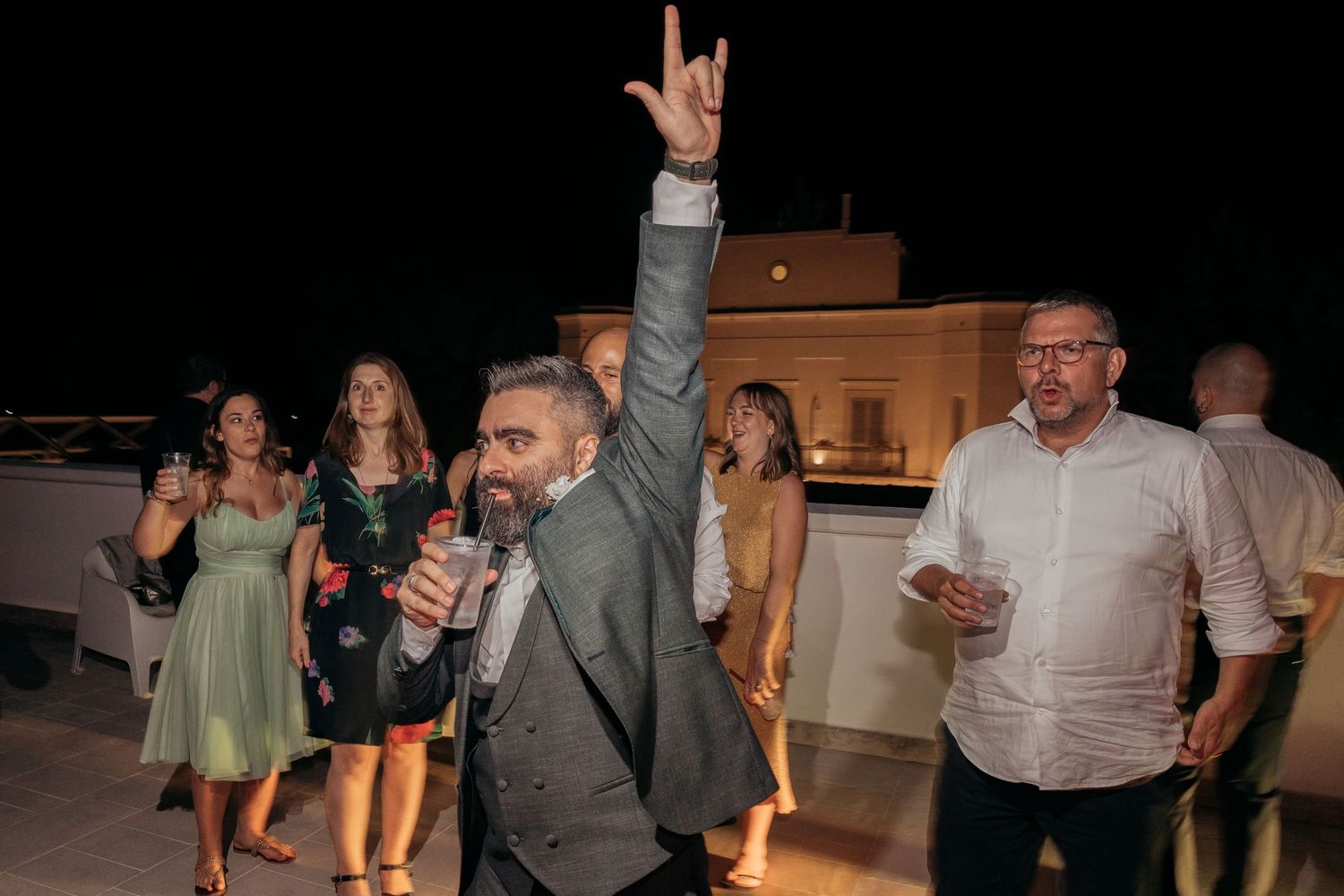 Wedding guest raises hand in celebration during outdoor reception party.