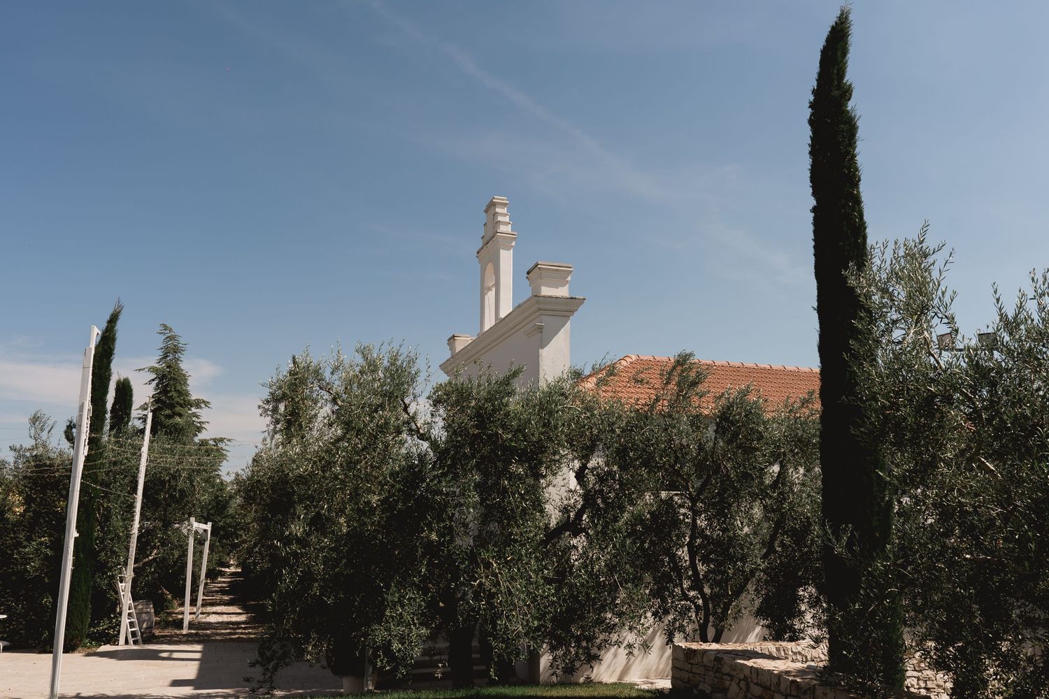 Mediterranean villa with white walls and cypress trees against a blue sky.