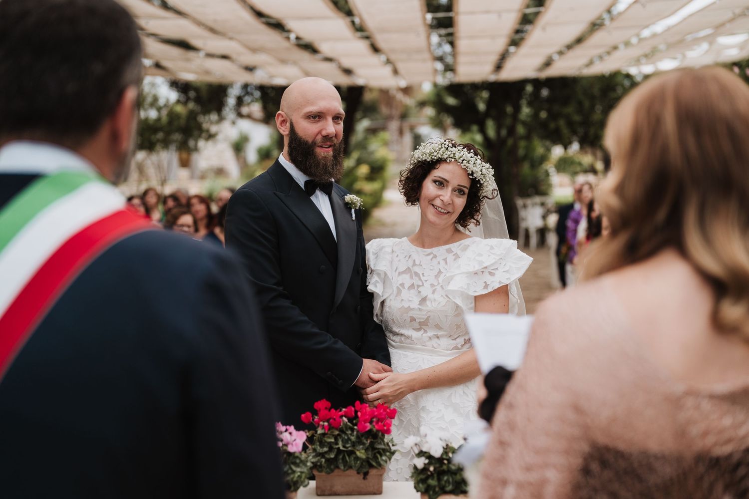 Wedding ceremony in a garden setting with guests and floral decorations.