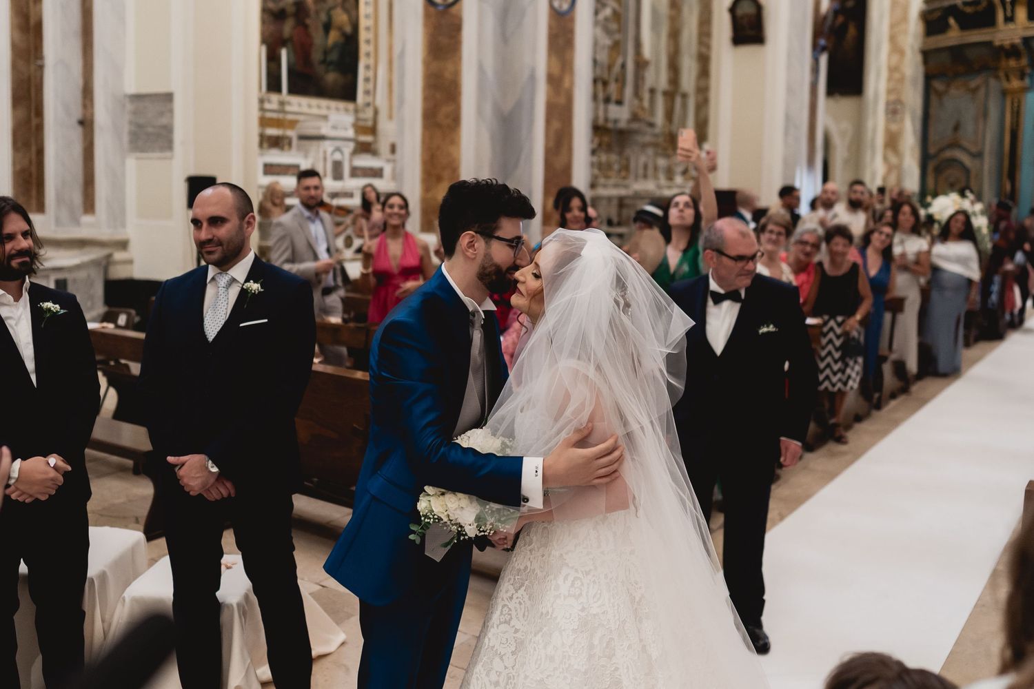 Wedding ceremony taking place in grand church aisle with architectural details.