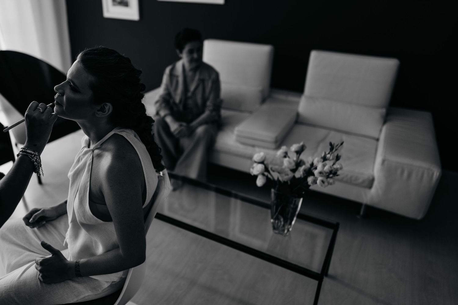 Black and white image of people in a modern living room with white couches.