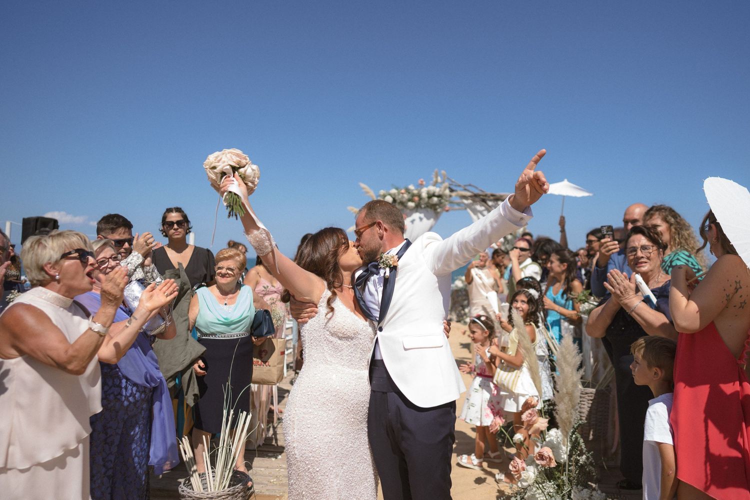Newlyweds celebrate with guests during outdoor beach ceremony recessional.