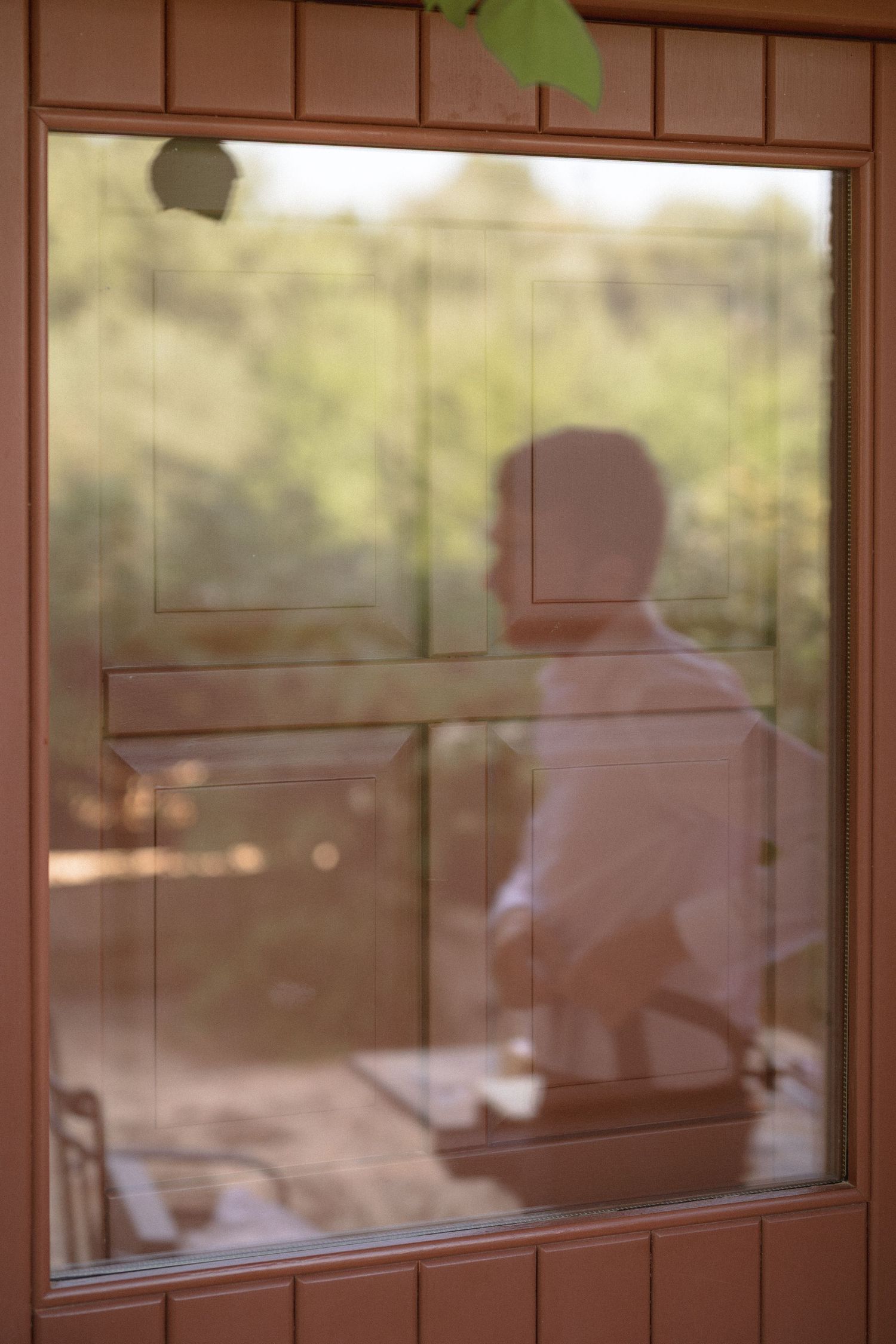 Silhouette seen through a window frame with soft natural lighting and bokeh effects.