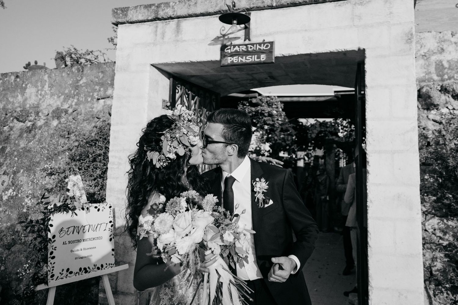Black and white photo of guests mingling at a rustic wedding venue.