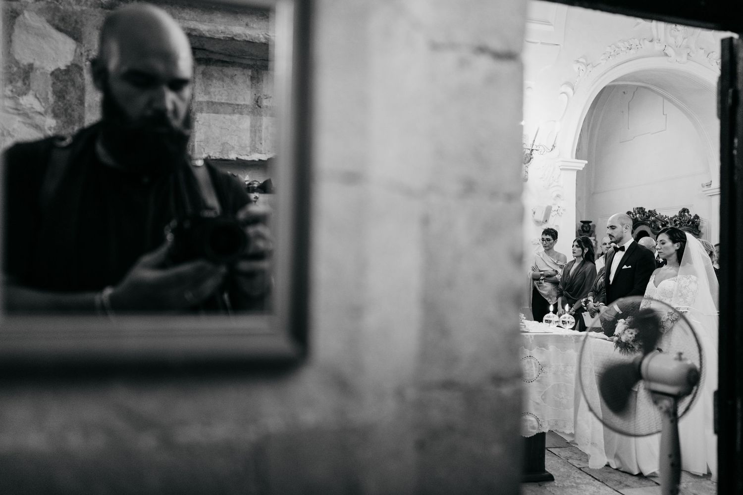 A creative wedding photo composition showing guests reflected in a mirror at a stone venue.