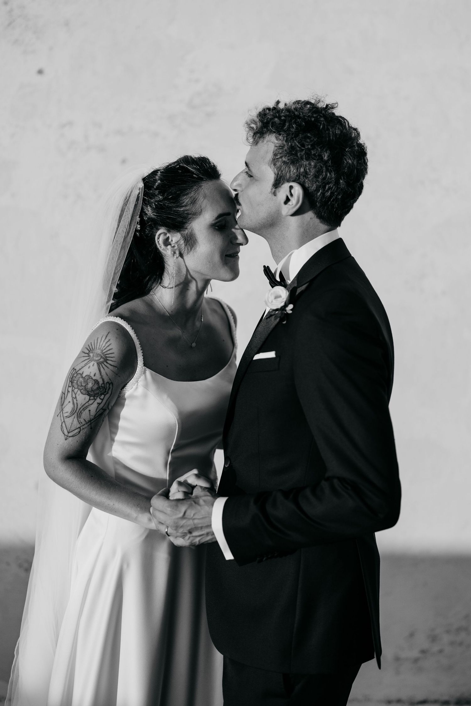 Black and white intimate portrait of newlyweds in formal wedding attire.