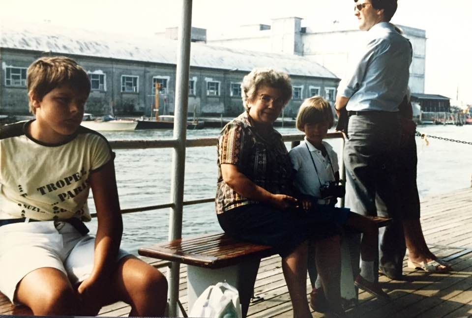 People relaxing on a wooden dock overlooking a waterfront on a sunny day.