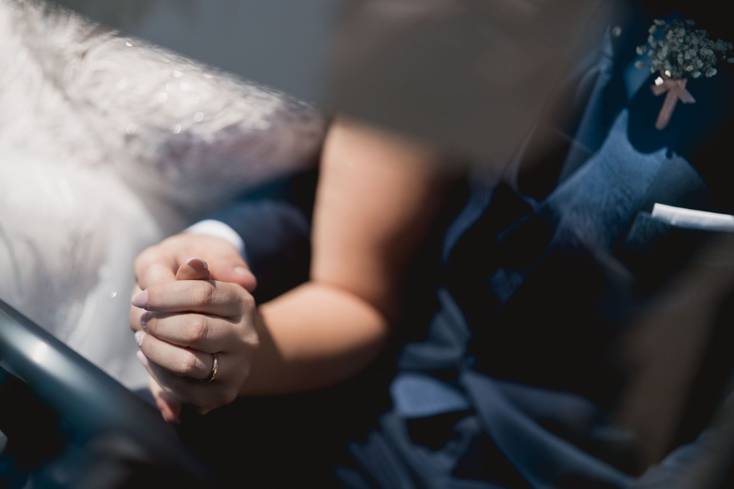 Close-up of clasped hands in formal wedding attire.