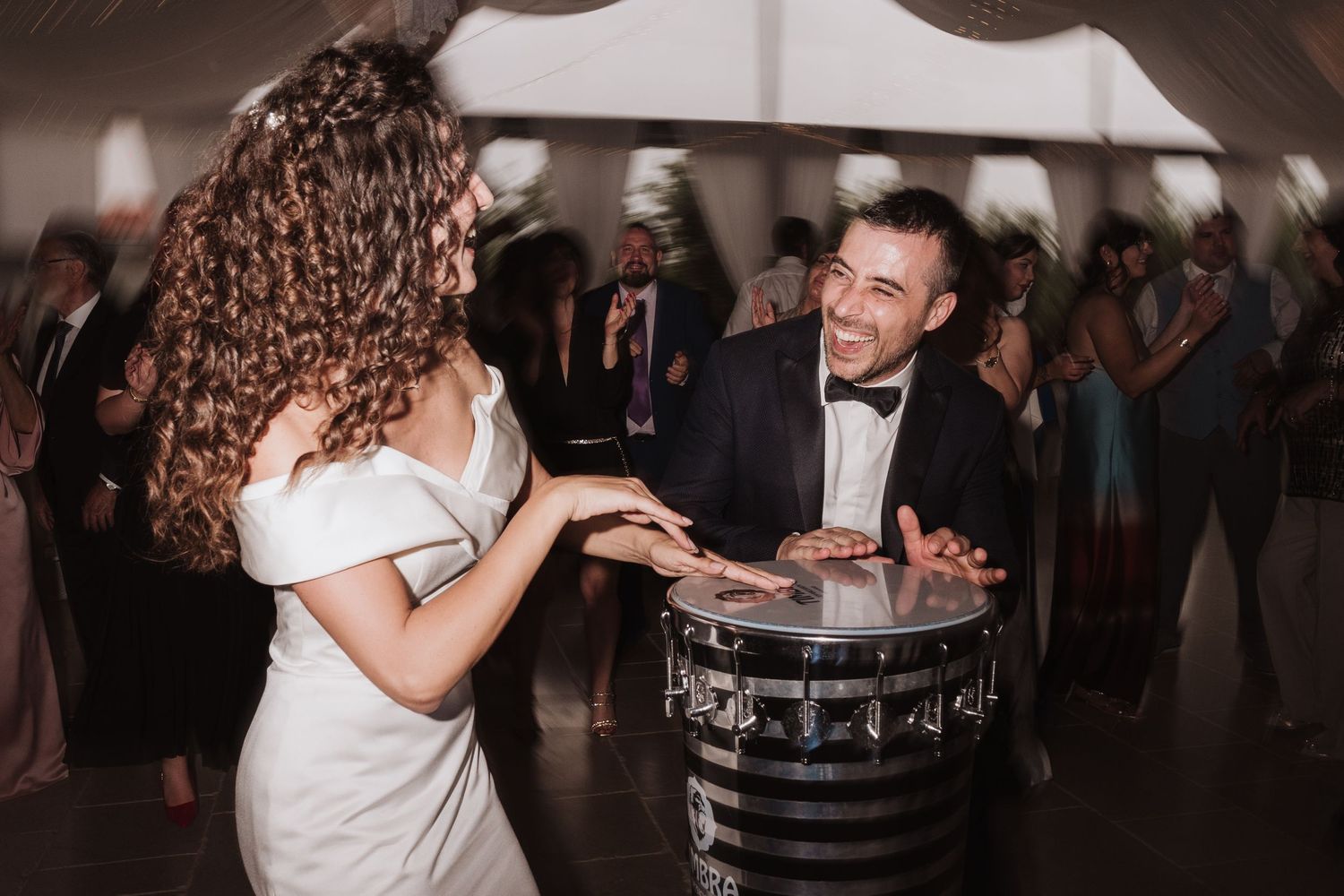 Wedding celebration with dancing near decorative drum under tent.