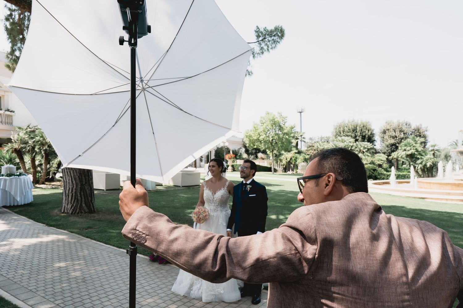 Photography crew with lighting equipment capturing a wedding moment outdoors.