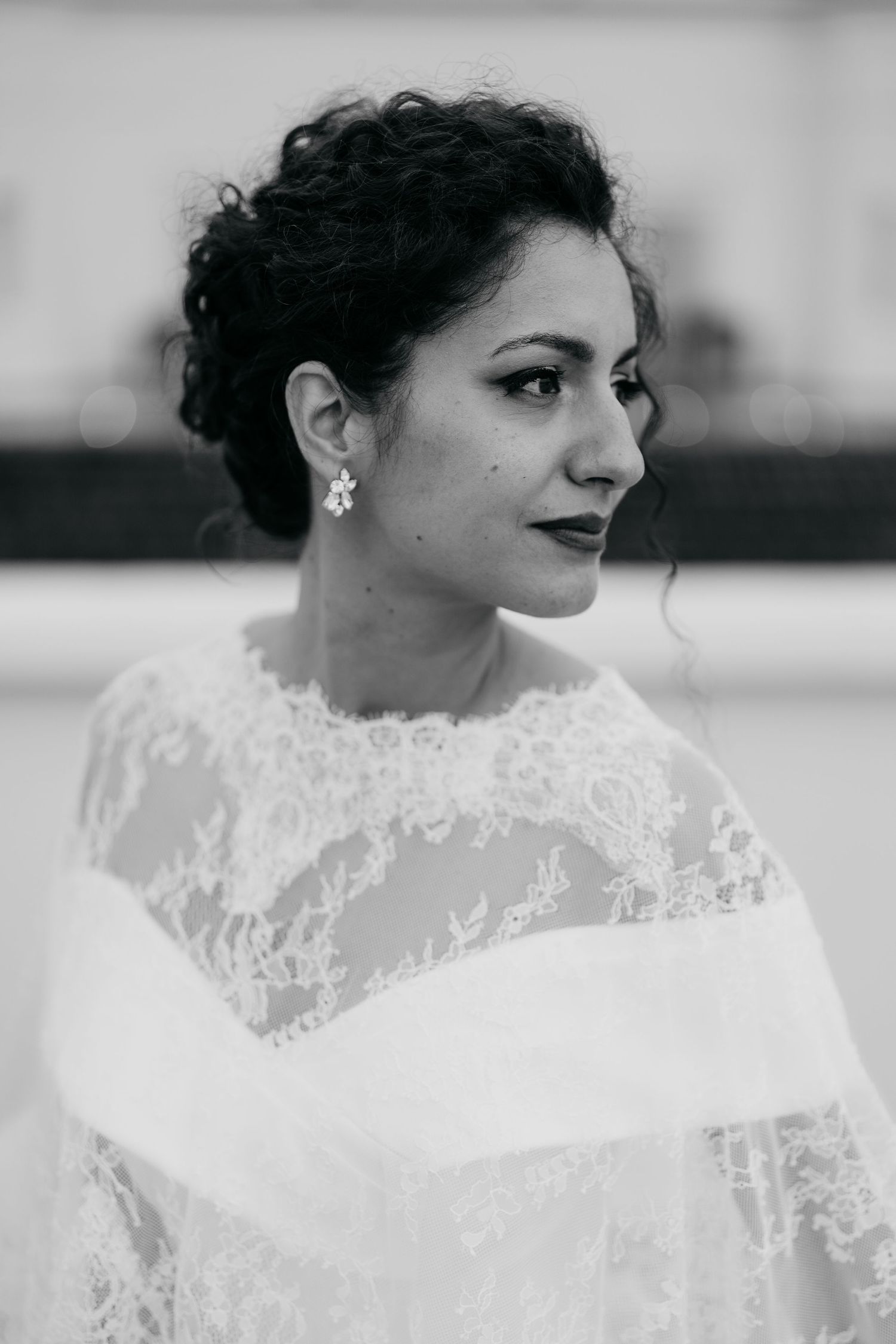 Black and white portrait of bride wearing lace wedding dress and elegant makeup.
