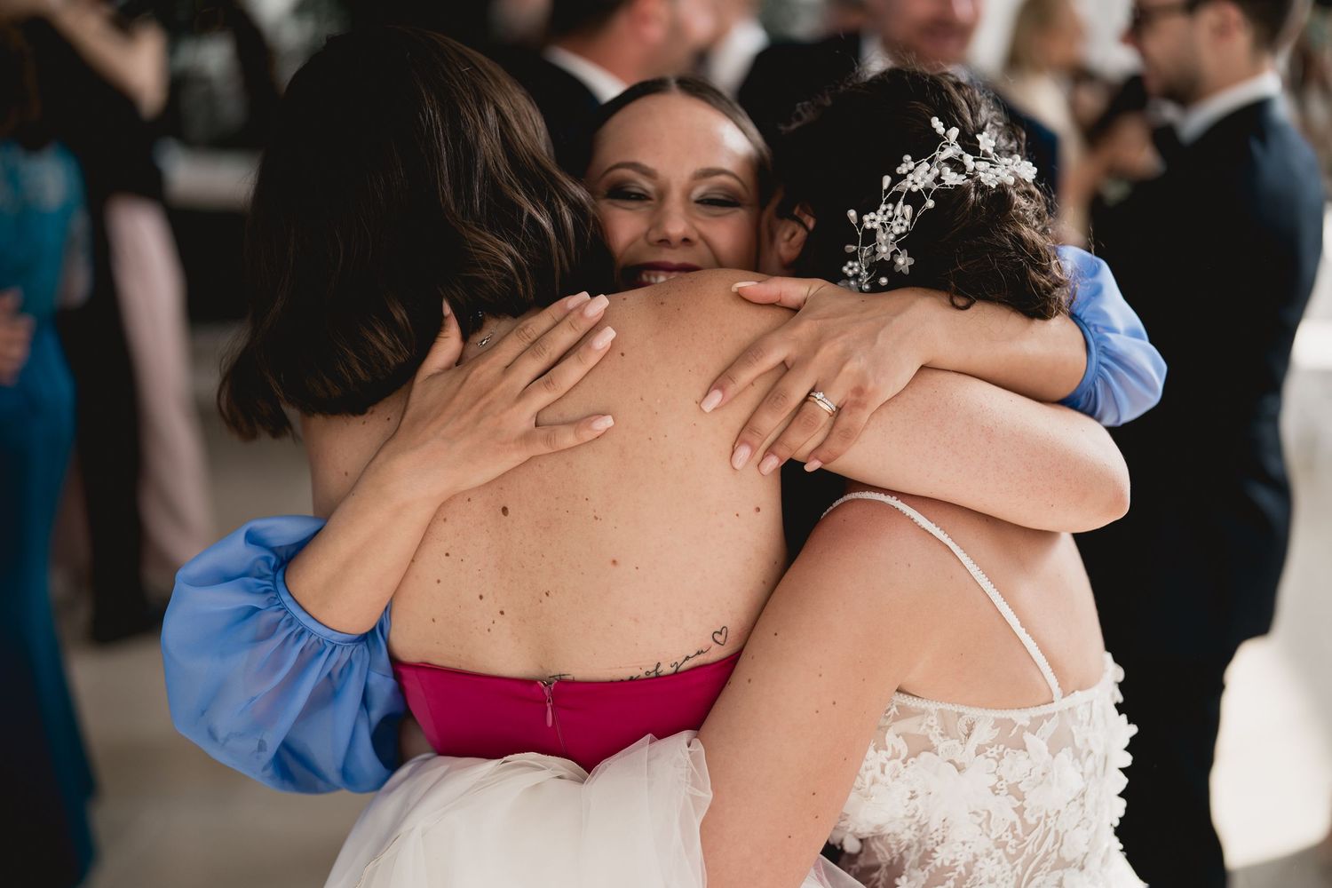 Emotional embrace shared during wedding celebration under white tent.