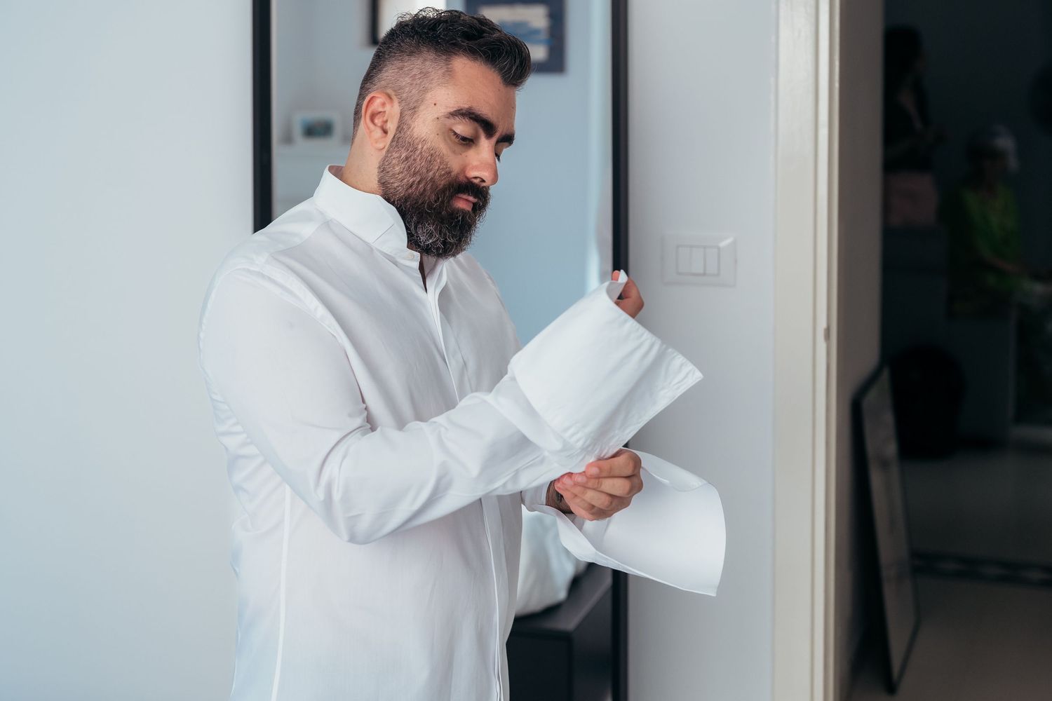 Person in white dress shirt adjusting sleeves.
