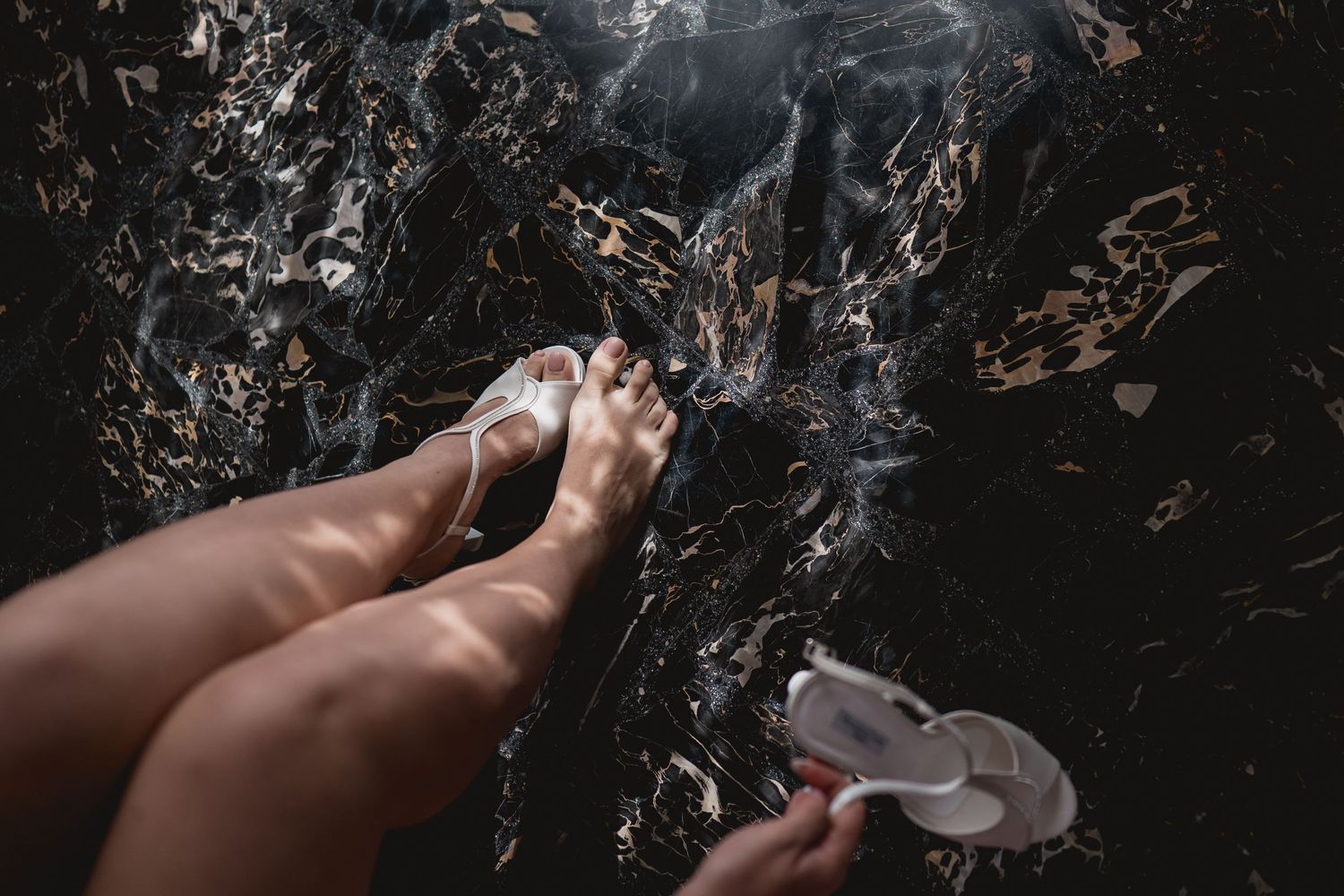 A hand holding a smoking cigarette against a dark textured background with smoke wisps in the air.