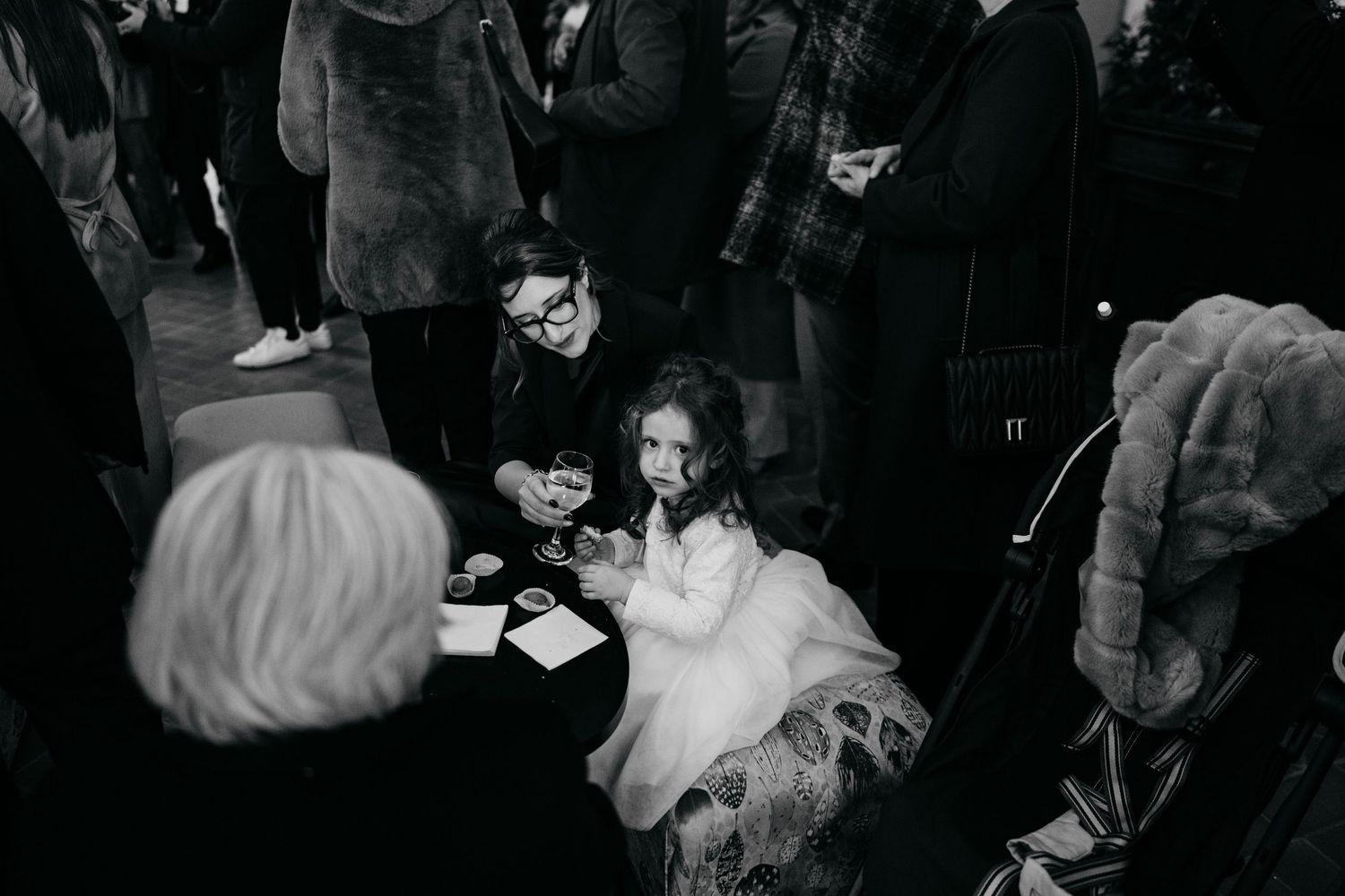Black and white photo of a child in a tulle skirt at a wedding reception.