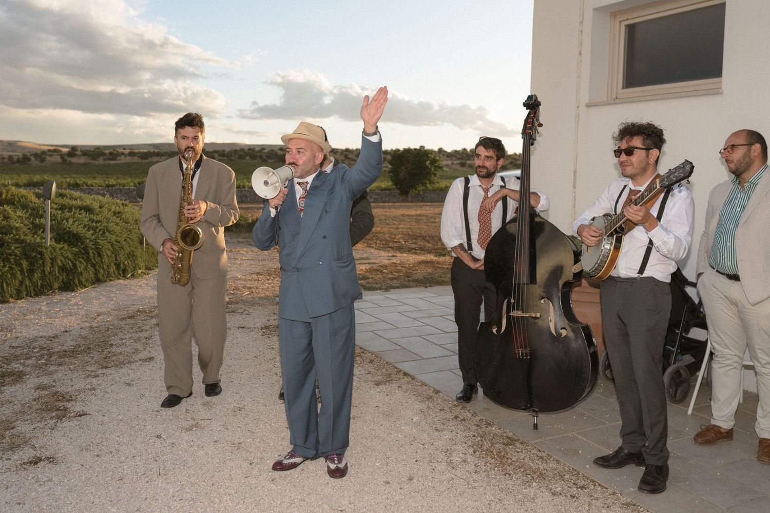 Wedding guests mingle and socialize outside a white Mediterranean style building.