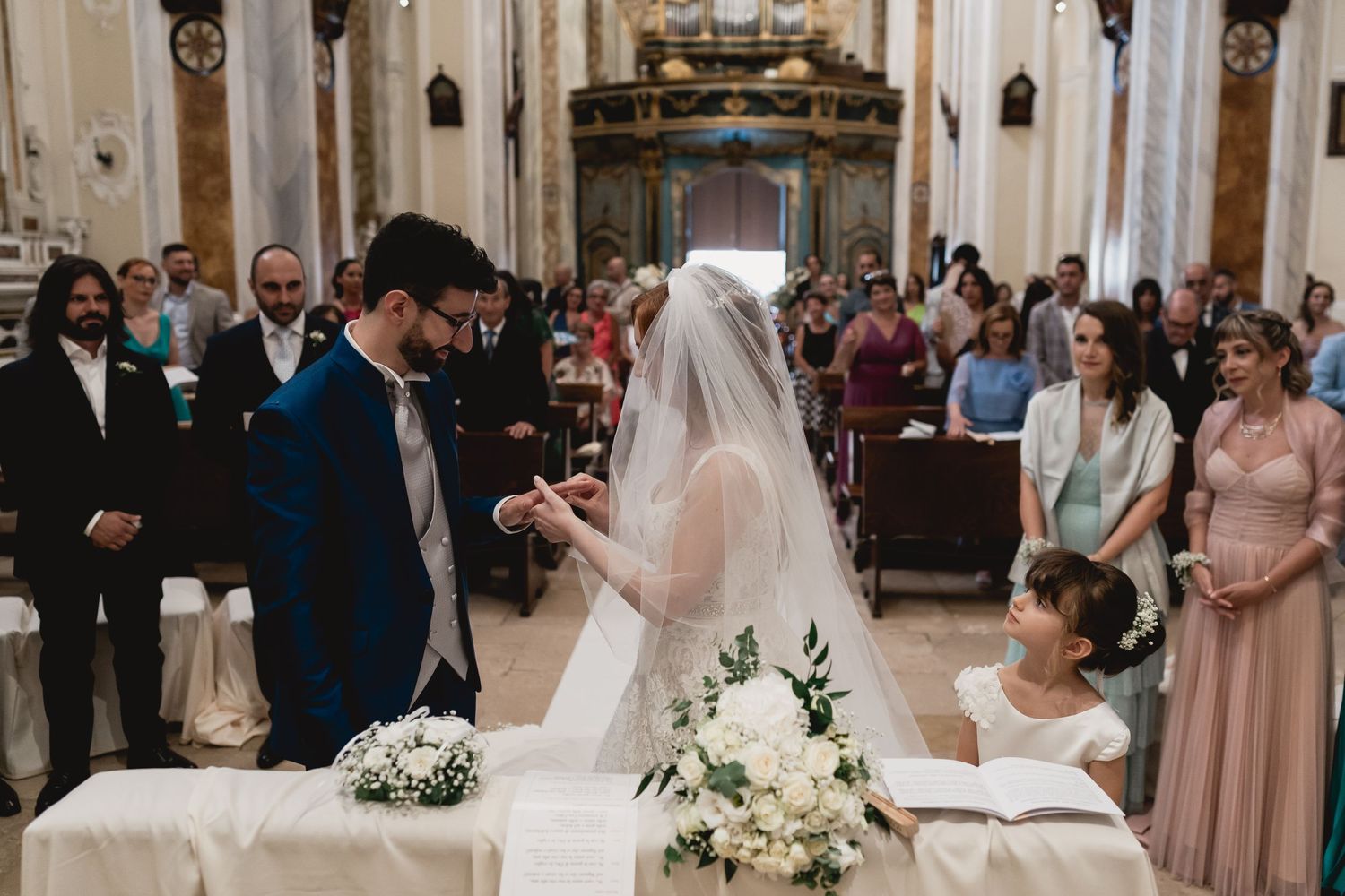 Intimate moment during wedding ceremony as couple completes paperwork at church altar.