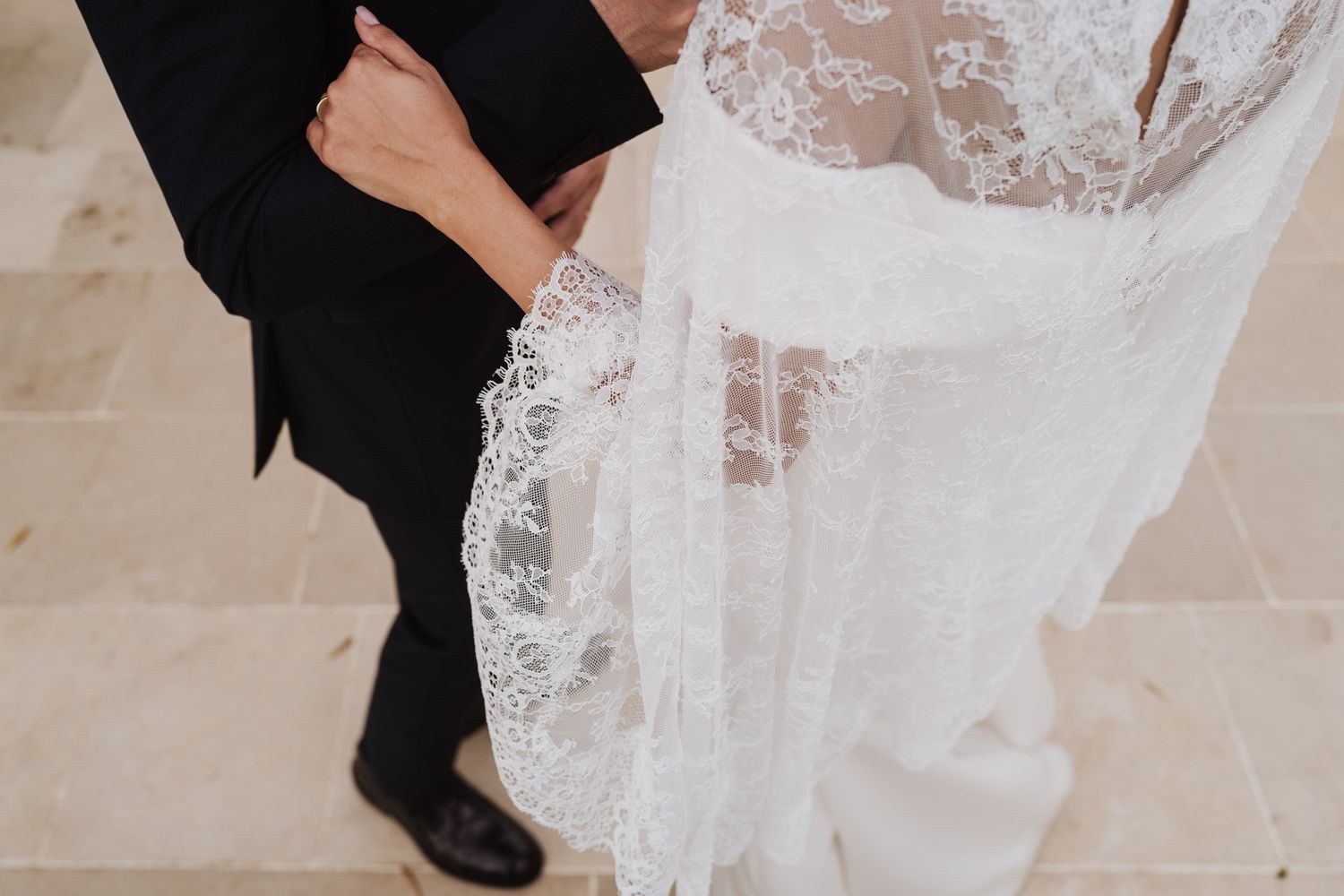 Close-up of formal wedding attire showing lace detail and black suit.