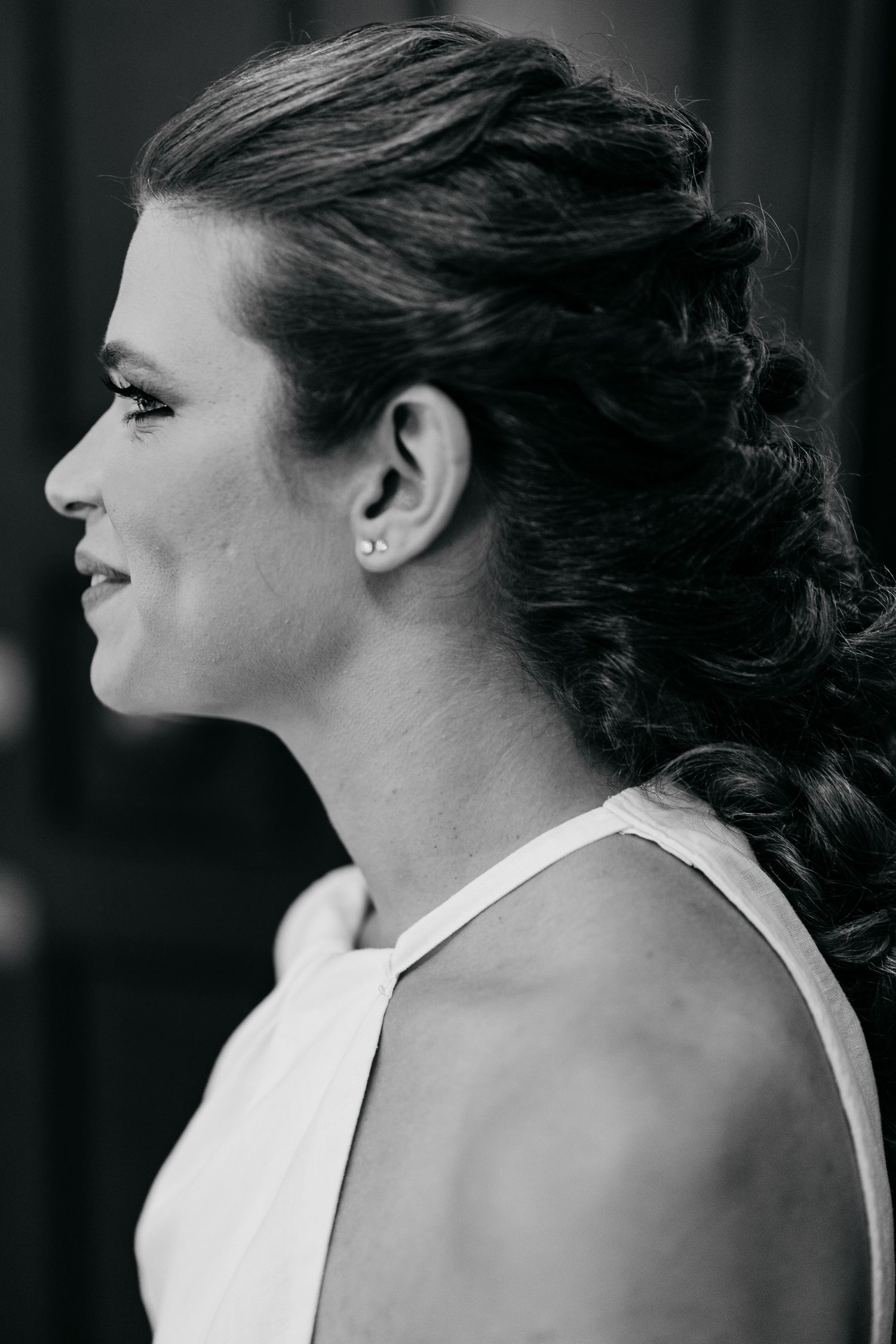 A side profile of an elegant updo hairstyle and formal white dress shown in black and white.